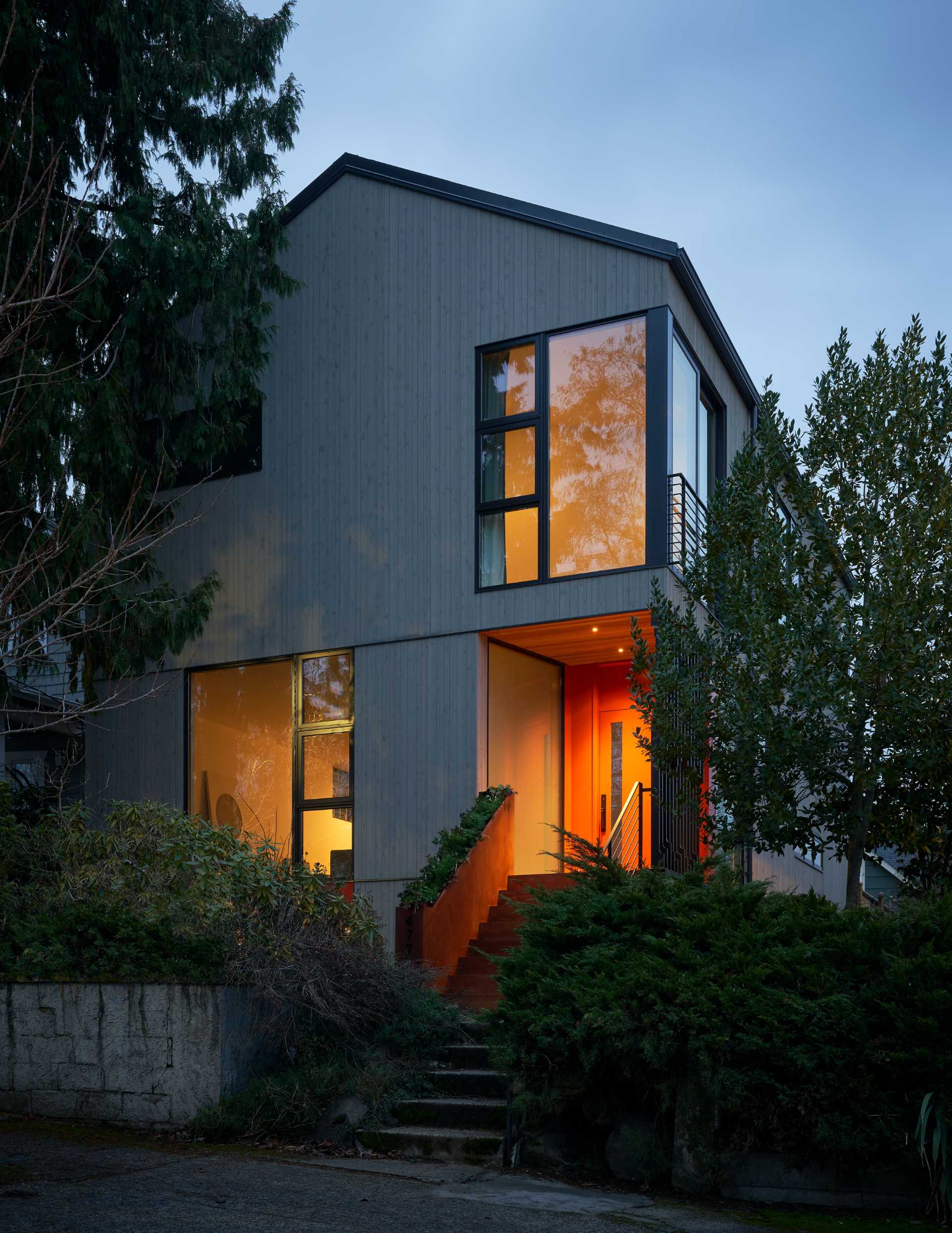 A modern house with a colorful front door, a steel planter, and a screen for added privacy.