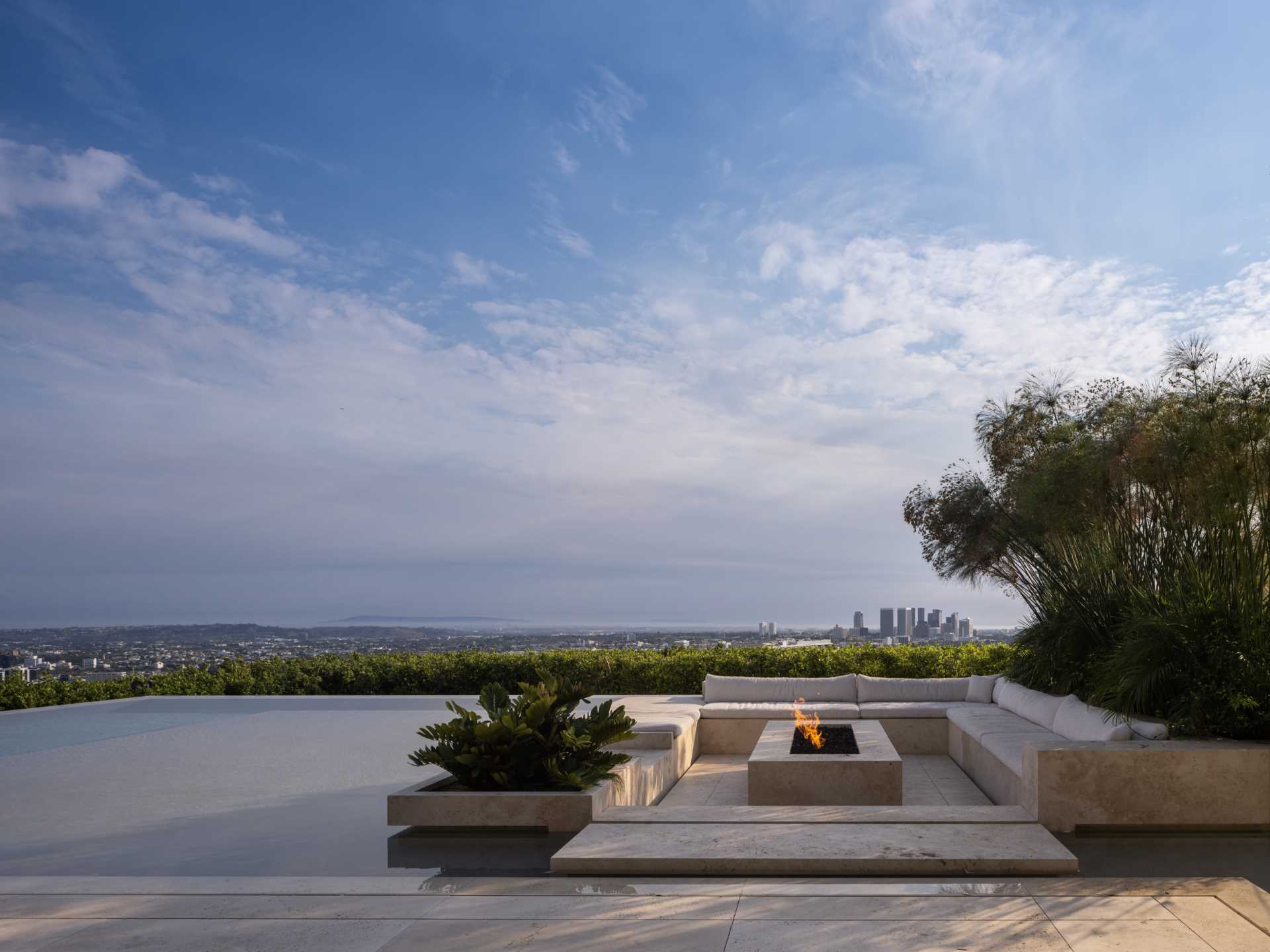 A modern house with a swimming pool and a sunken outdoor living room with a firepit.