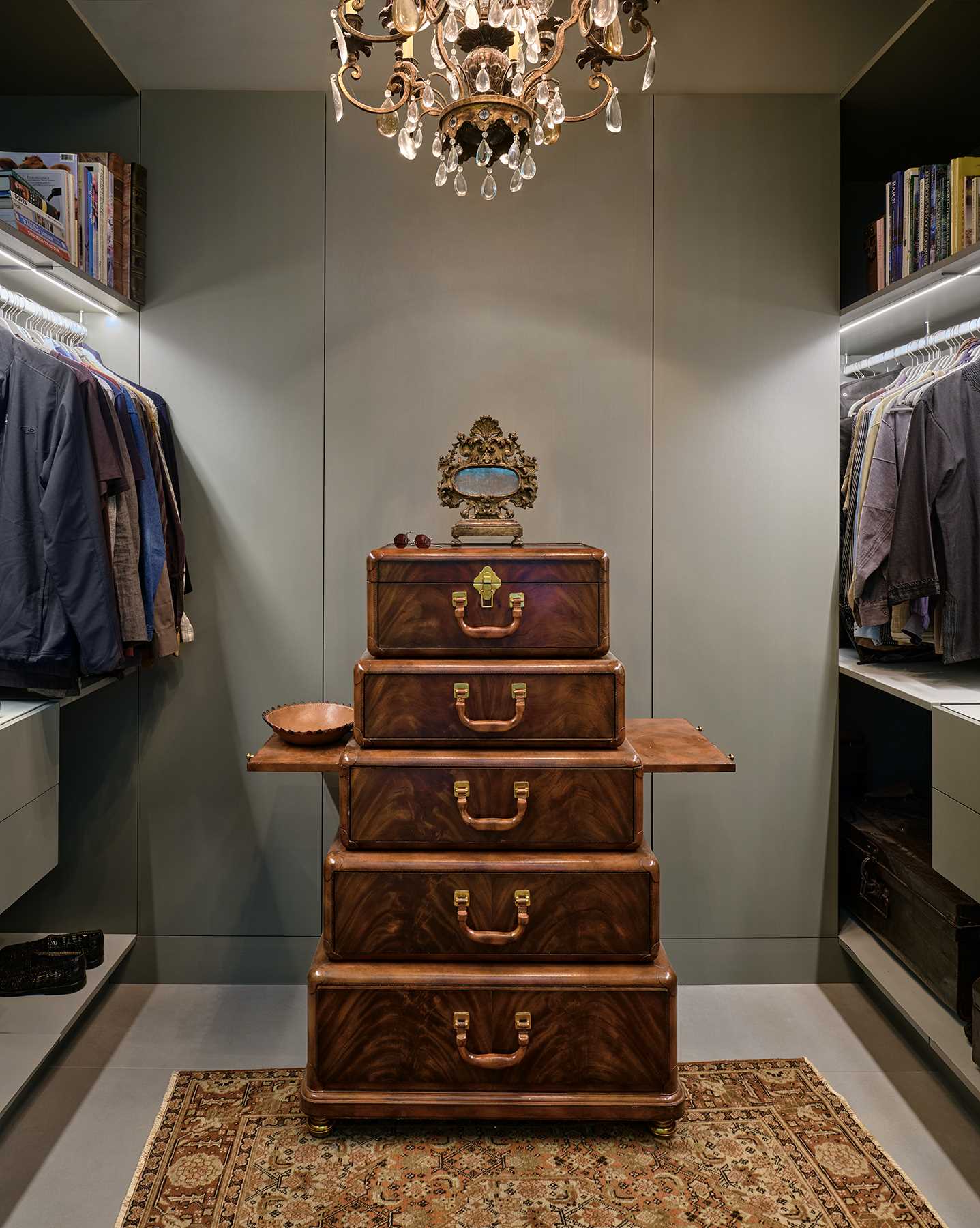 A walk-in closet with shelves that include under-mount lighting in addition to the chandelier.