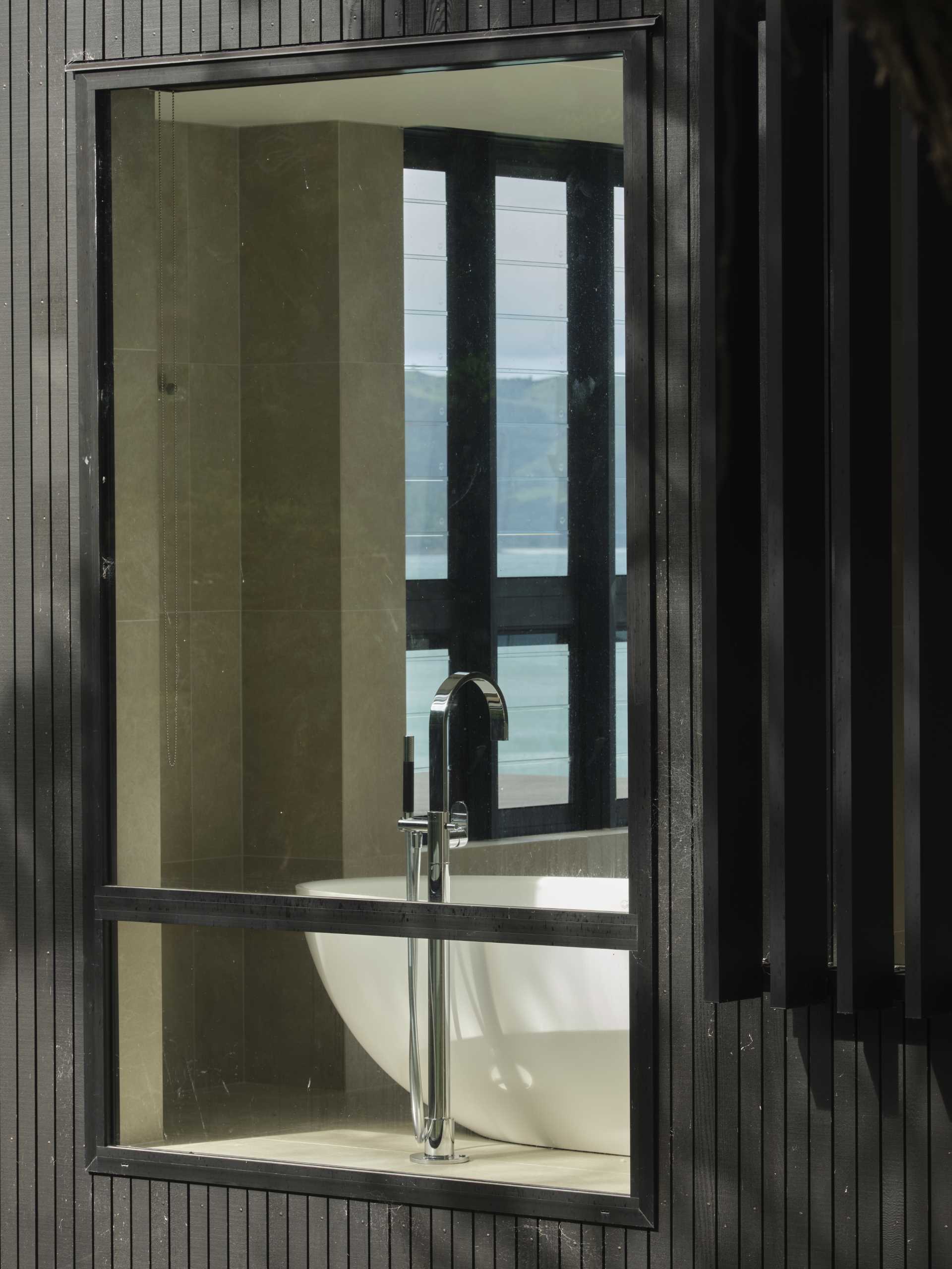 A modern bathroom with a freestanding bathtub and tall windows.