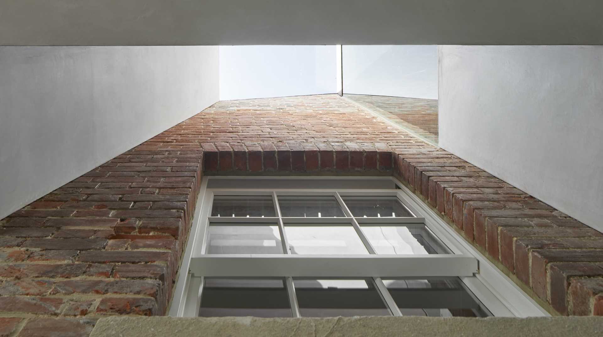 An old brick house with a new extension shows of the original brick walls and windows.