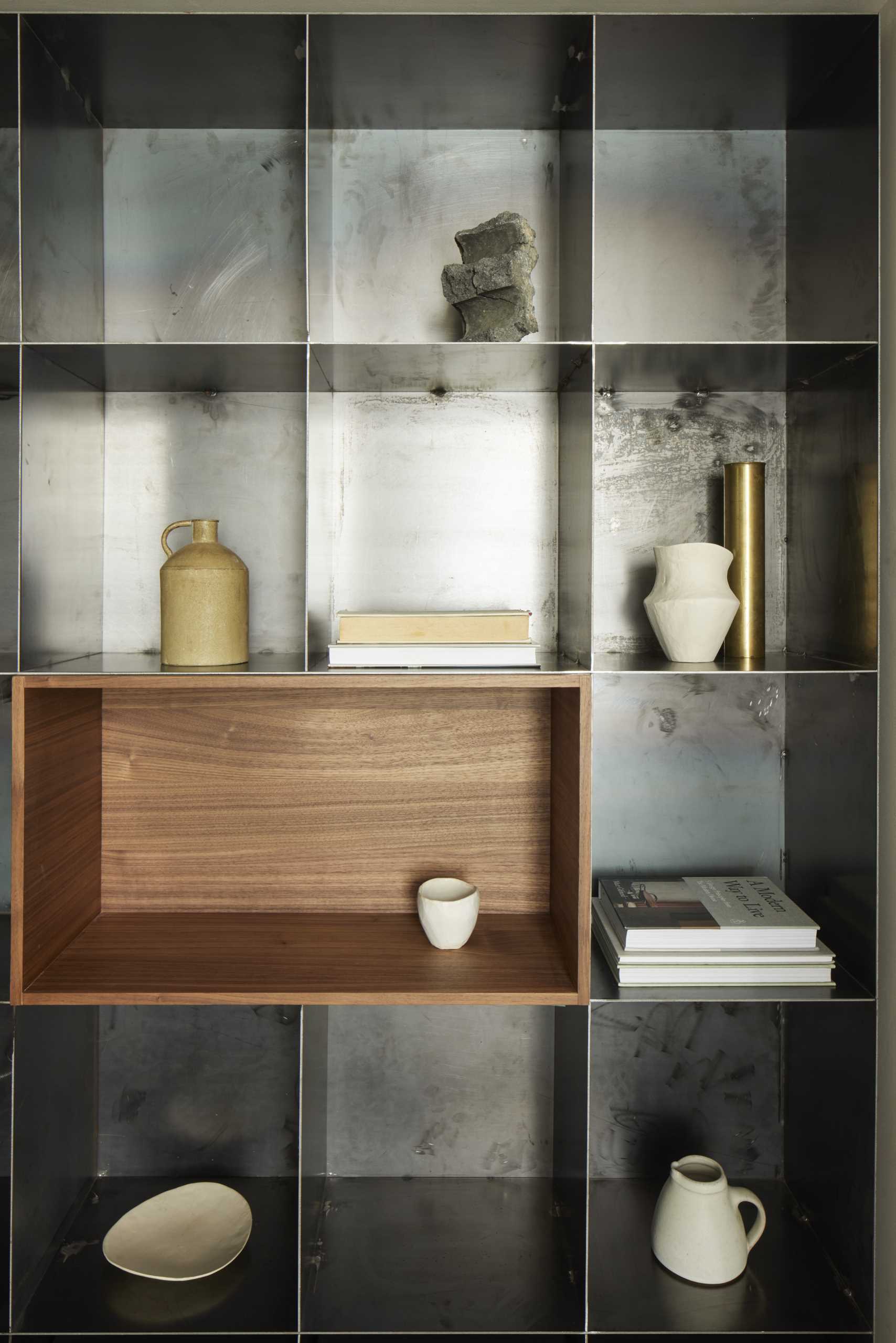 A modern metal bookshelf with a dark wood niche.