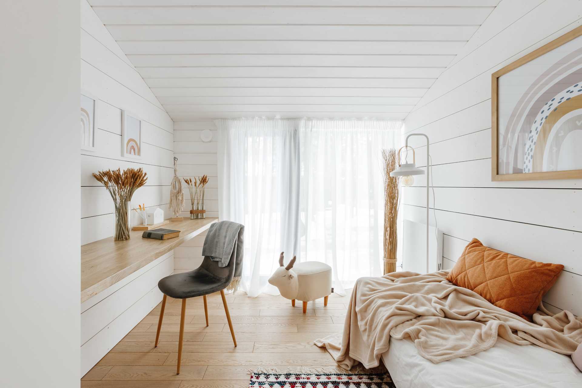 A bedroom for a child that includes a floating wood desk lining the wall.