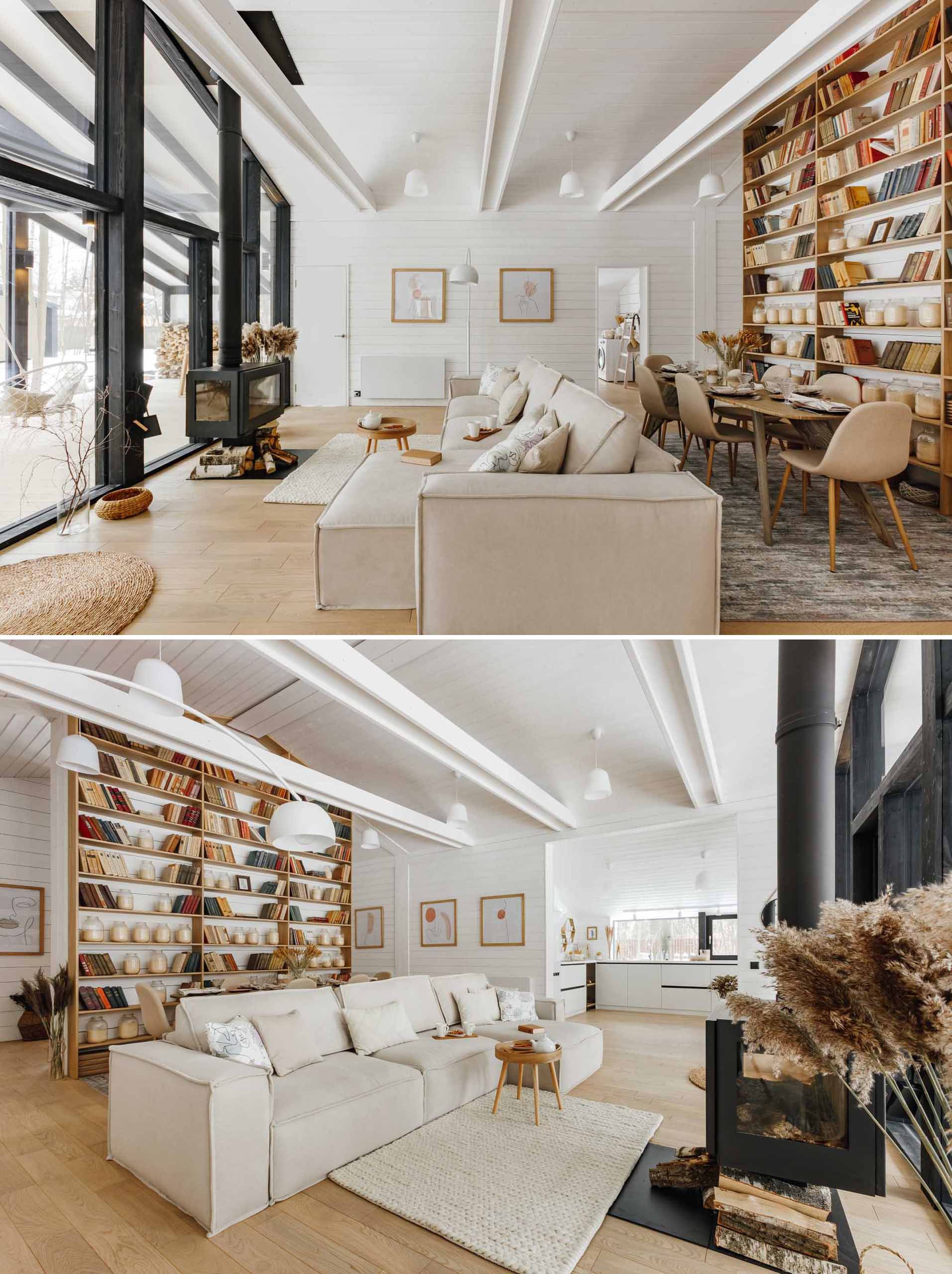 An open plan living room and dining area, that includes a fireplace, a wall of windows, and a floor-to-ceiling bookshelf.