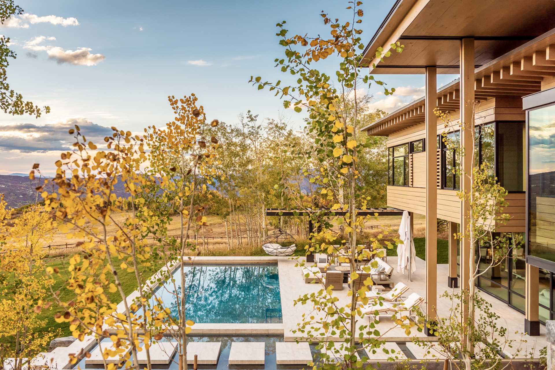 A modern mountain home with a swimming pool and water feature.