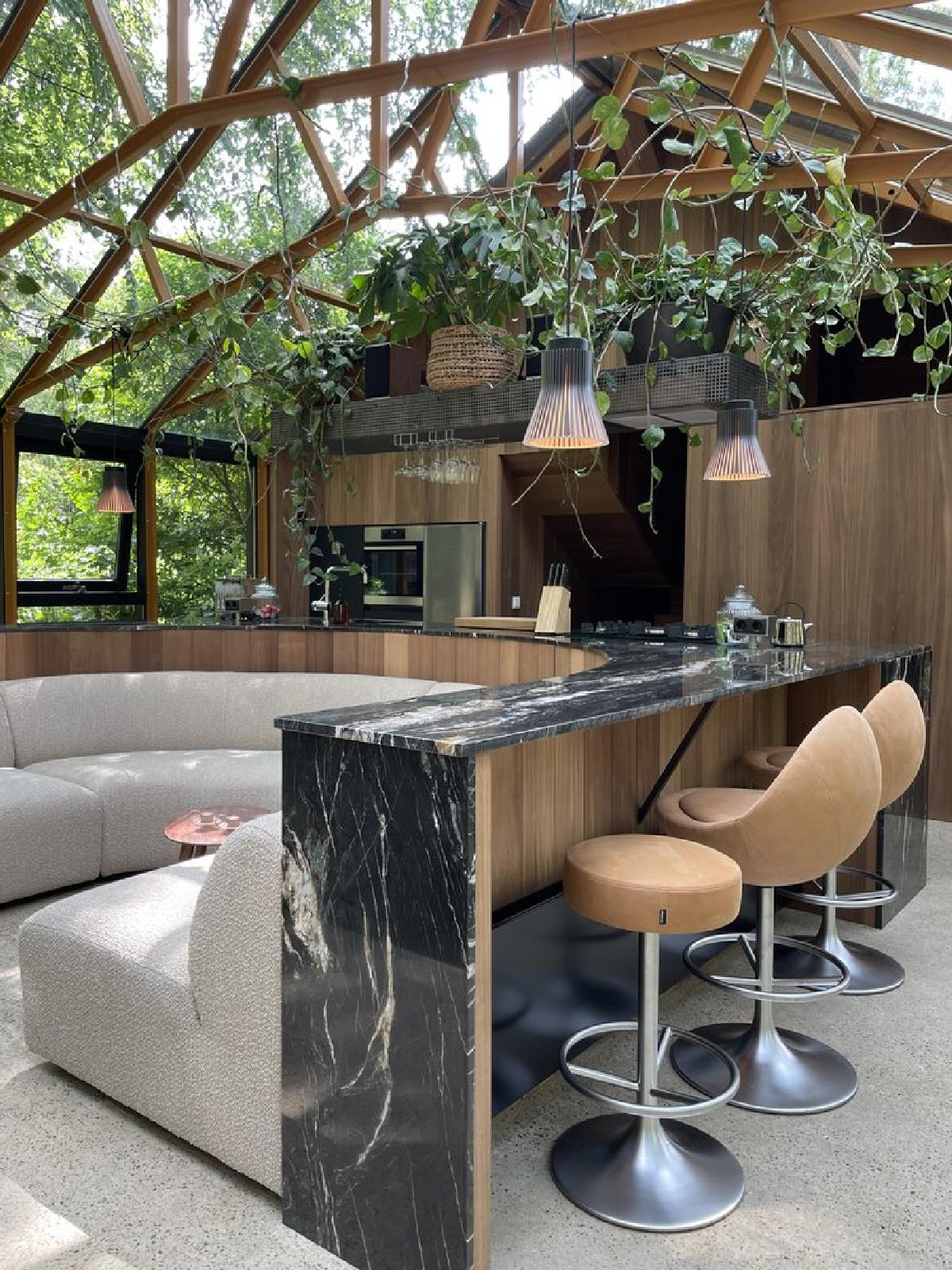 This bar which wraps around the curved couch, is clad in a Belvedere quartzite, and has stools as well as hidden lighting on each side.