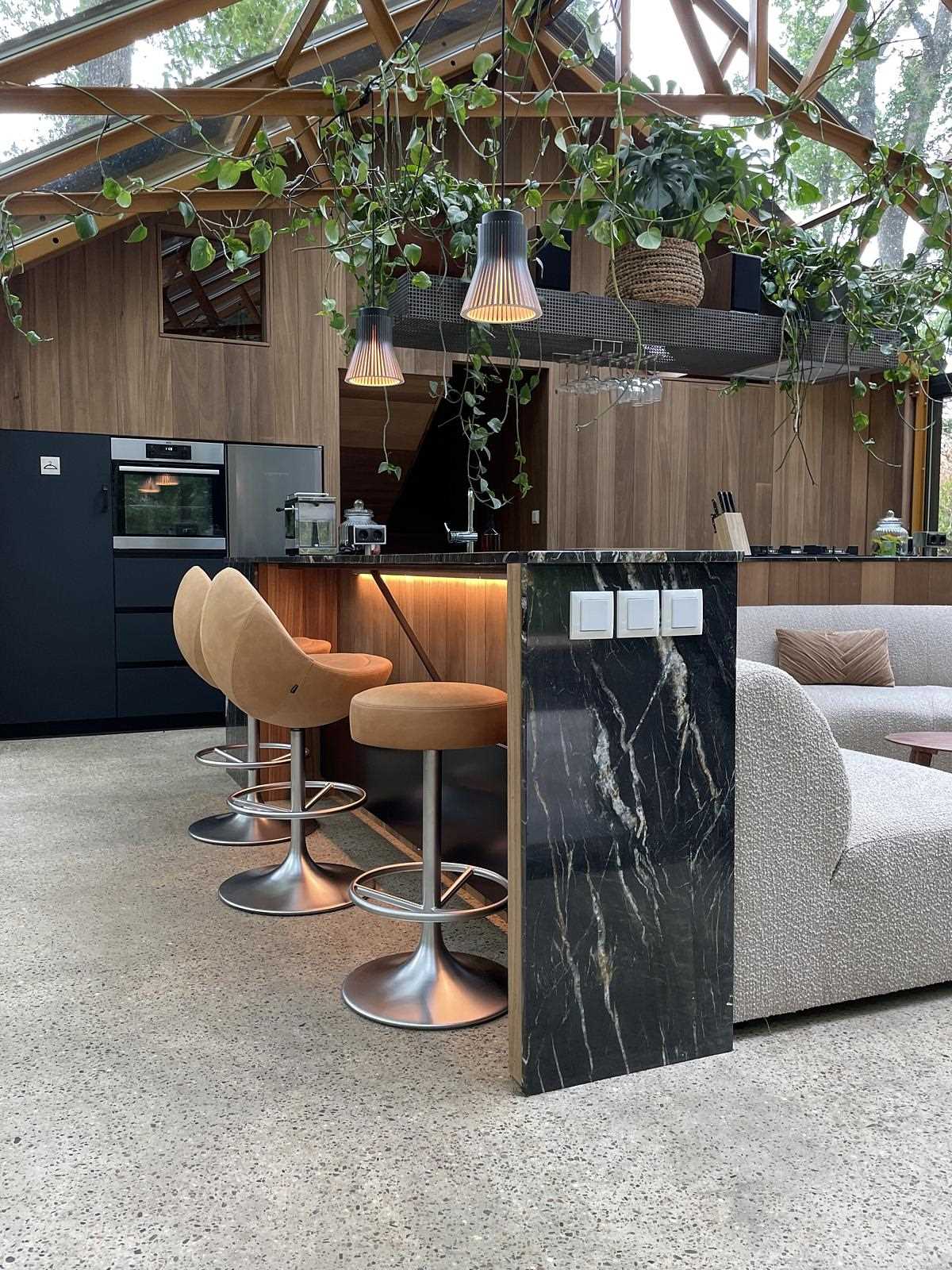 This bar which wraps around the curved couch, is clad in a Belvedere quartzite, and has stools as well as hidden lighting on each side.