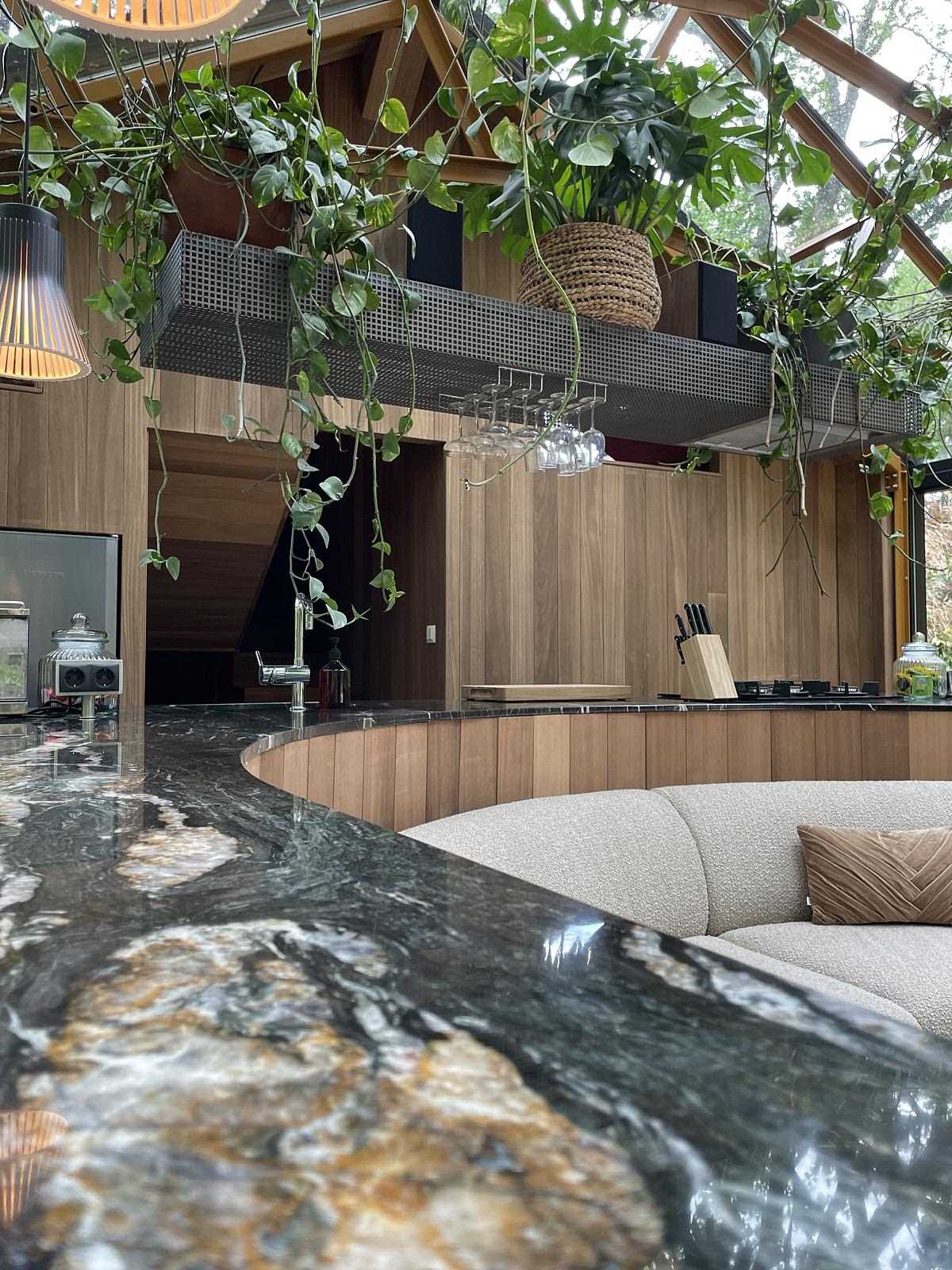 A curved Belvedere quartzite countertop connects through the kitchen, while the wood cabinets complement the wood structure of the home.