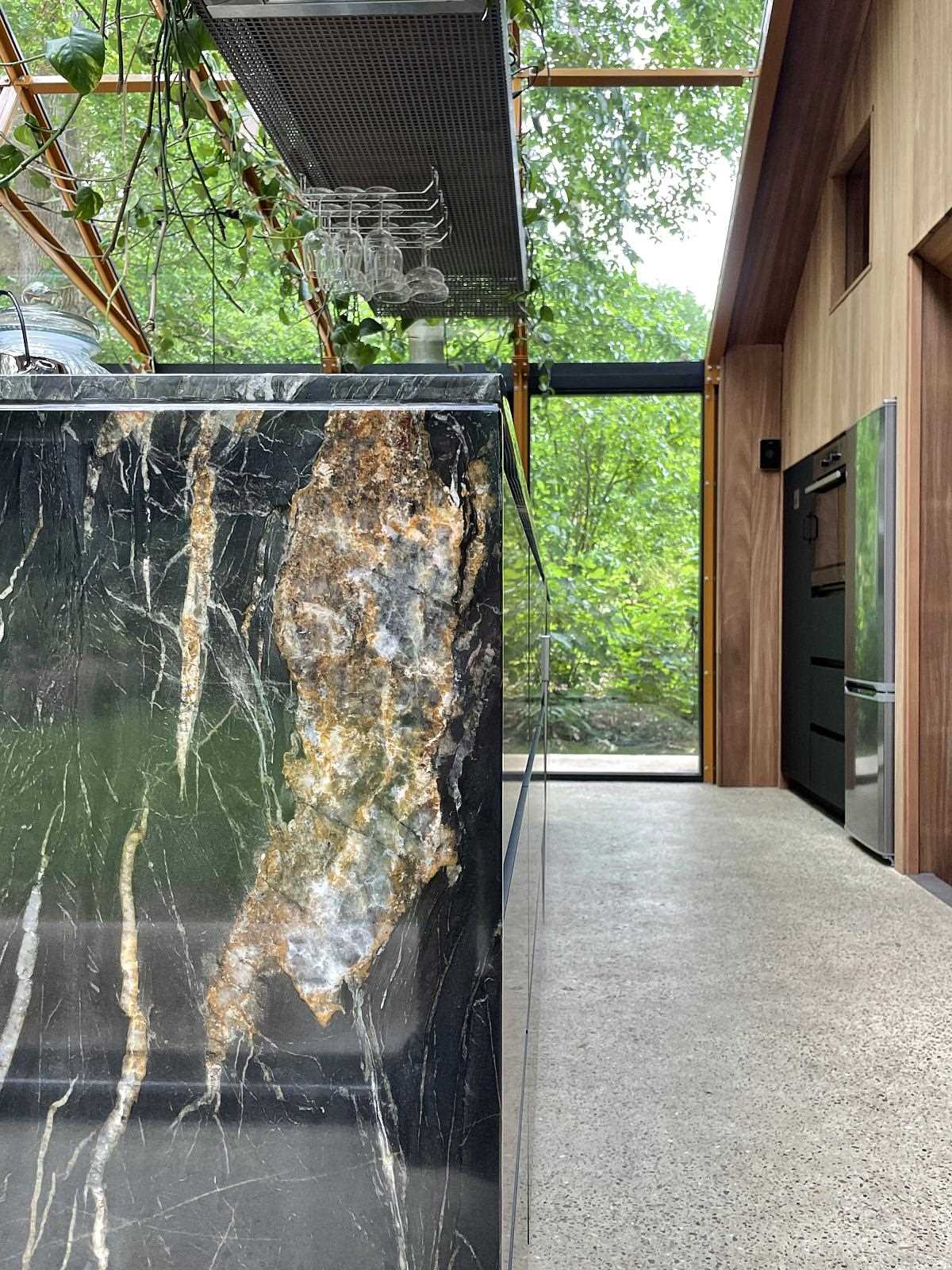 A curved Belvedere quartzite countertop connects through the kitchen, while the wood cabinets complement the wood structure of the home.