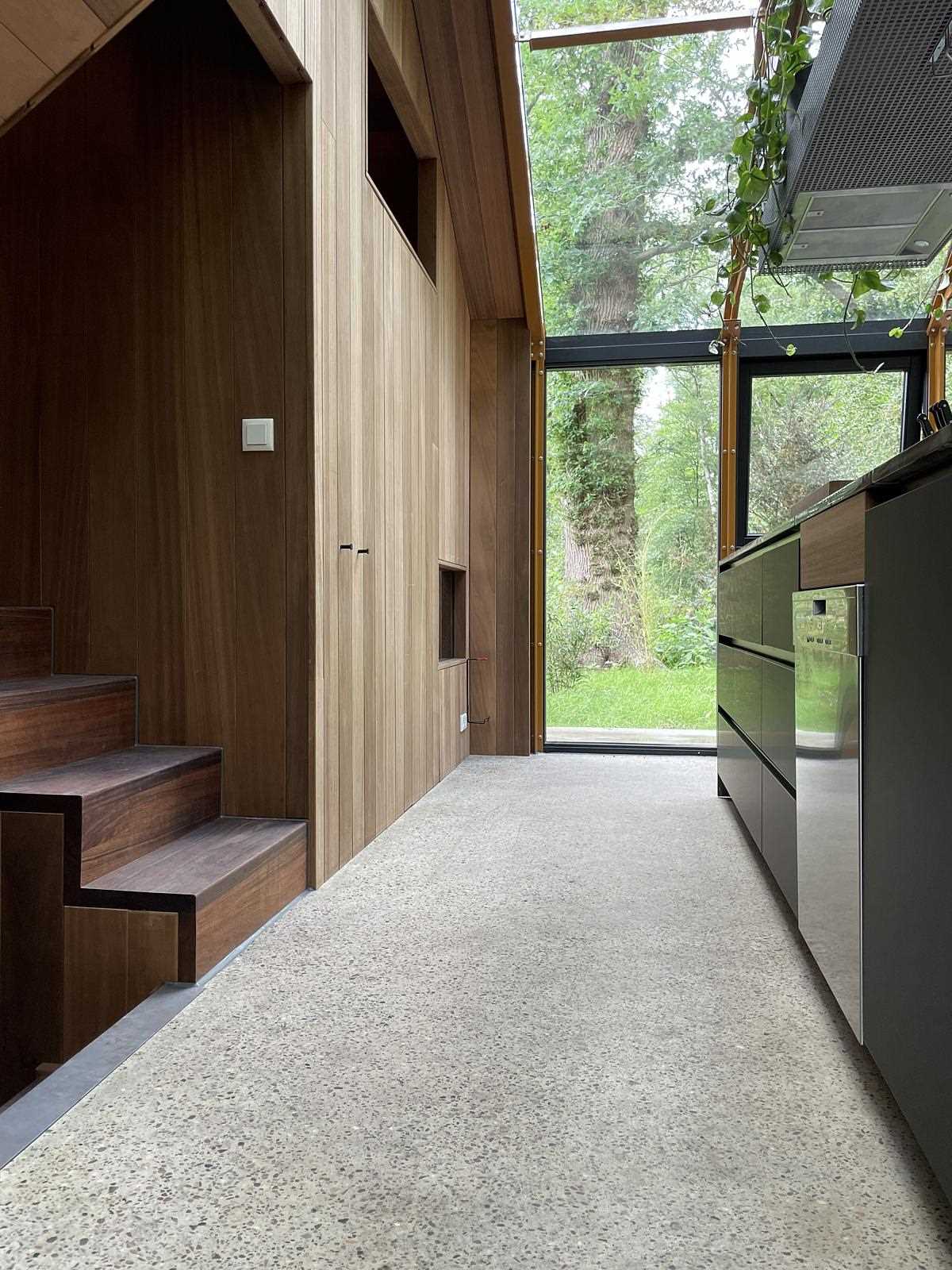 A modern kitchen with wood and black cabinets and drawers, and glass walls and ceiling.