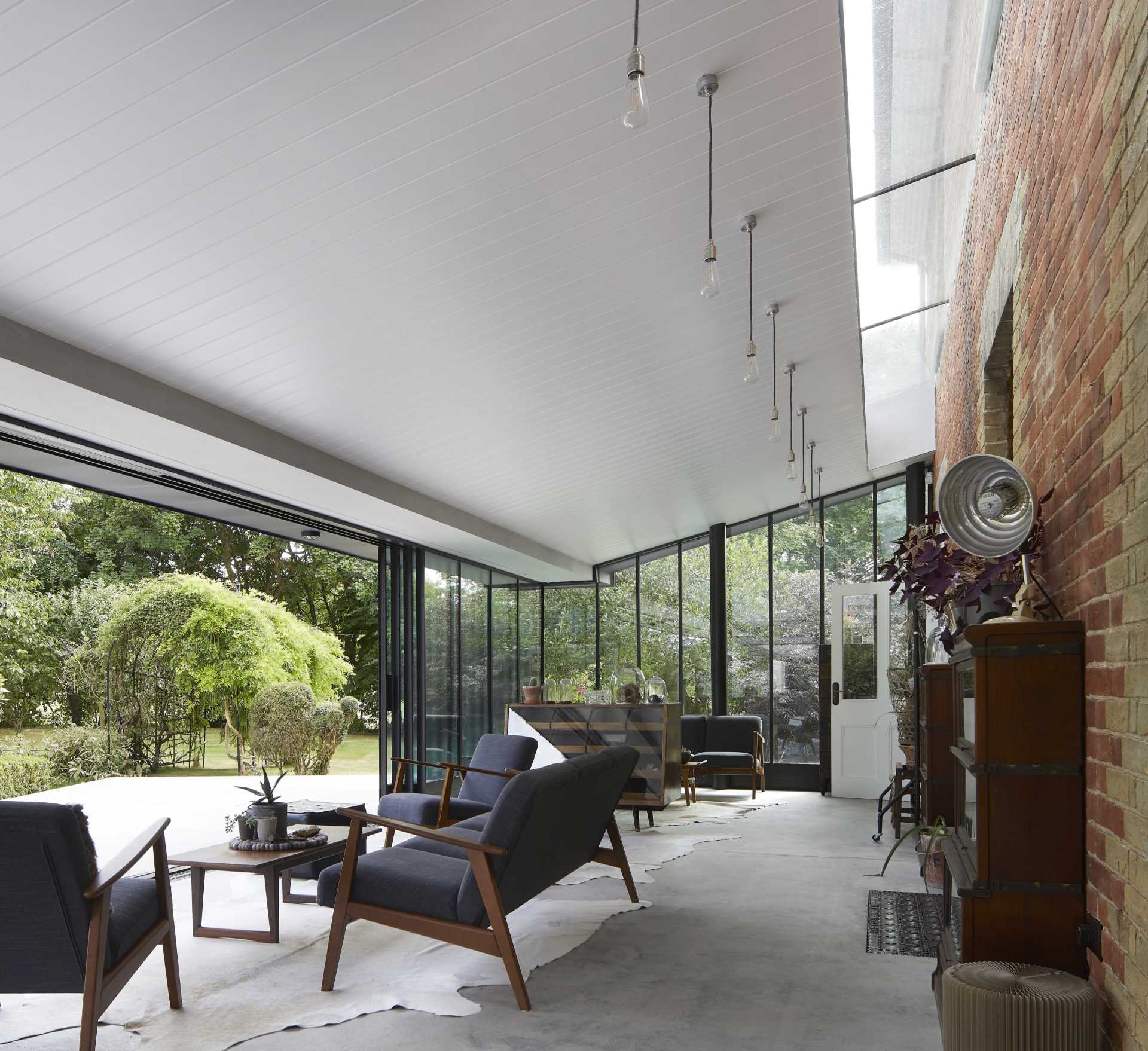 A modern house extension has sliding glass walls that open the living spaces to the landscaped garden.