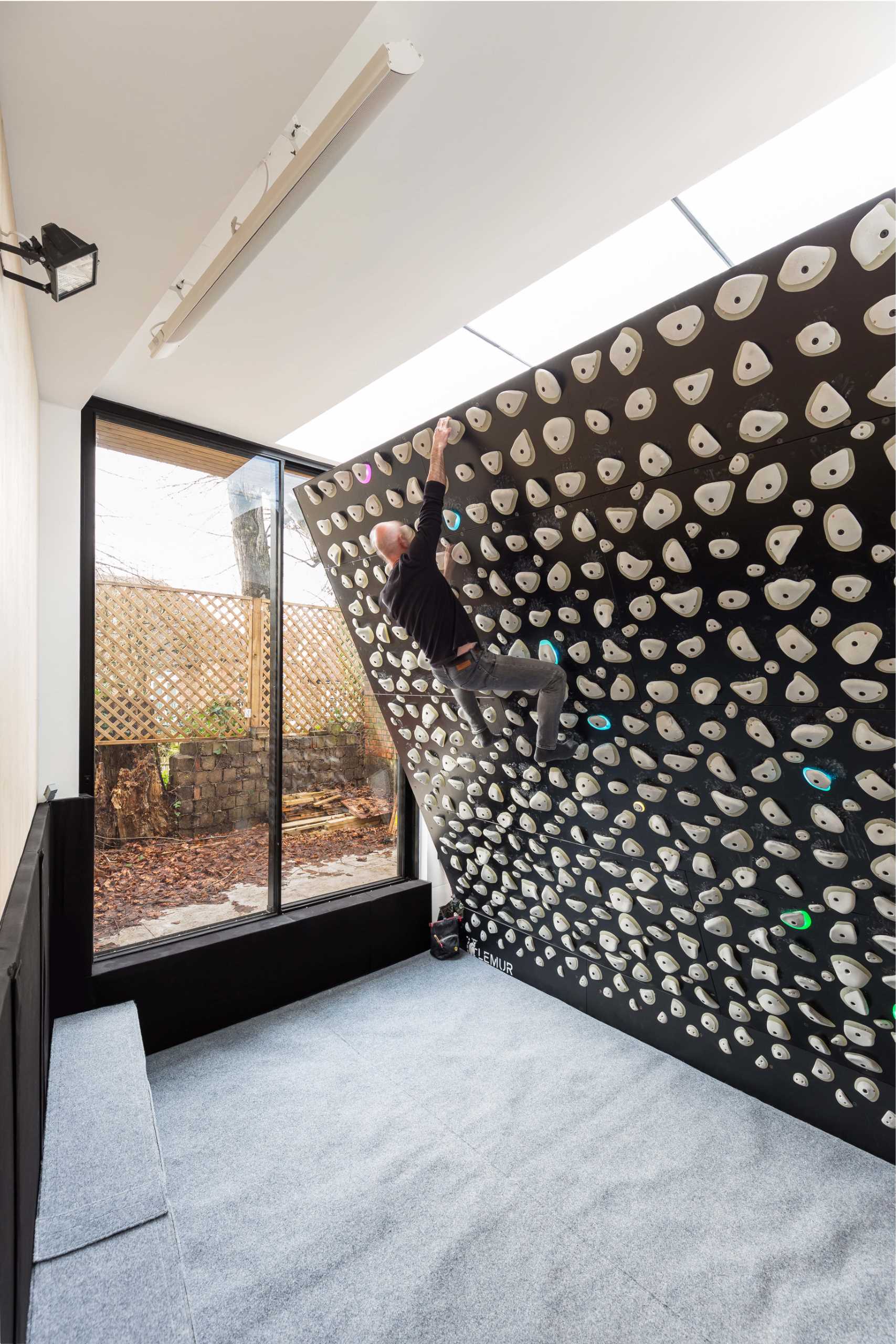 A backyard home office also includes a rock climbing gym with an adjustable wall.