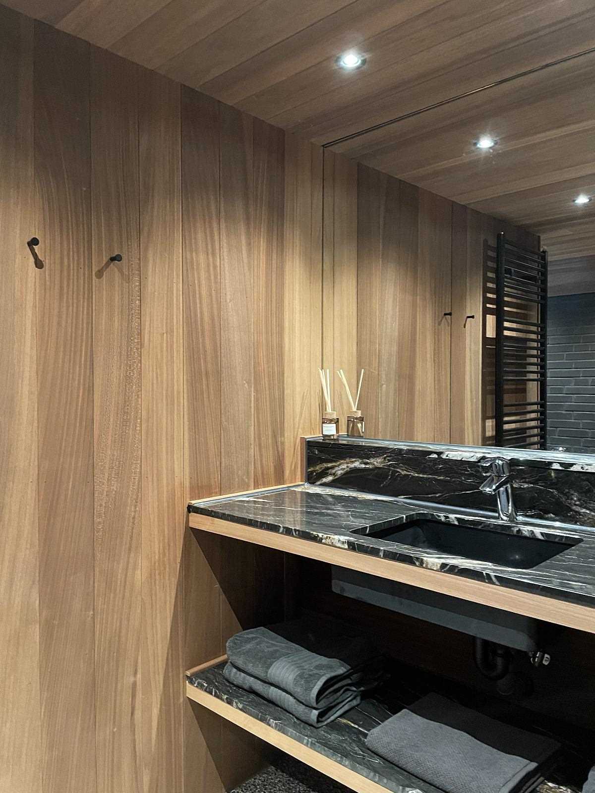 A modern bathroom with wood and black brick walls.