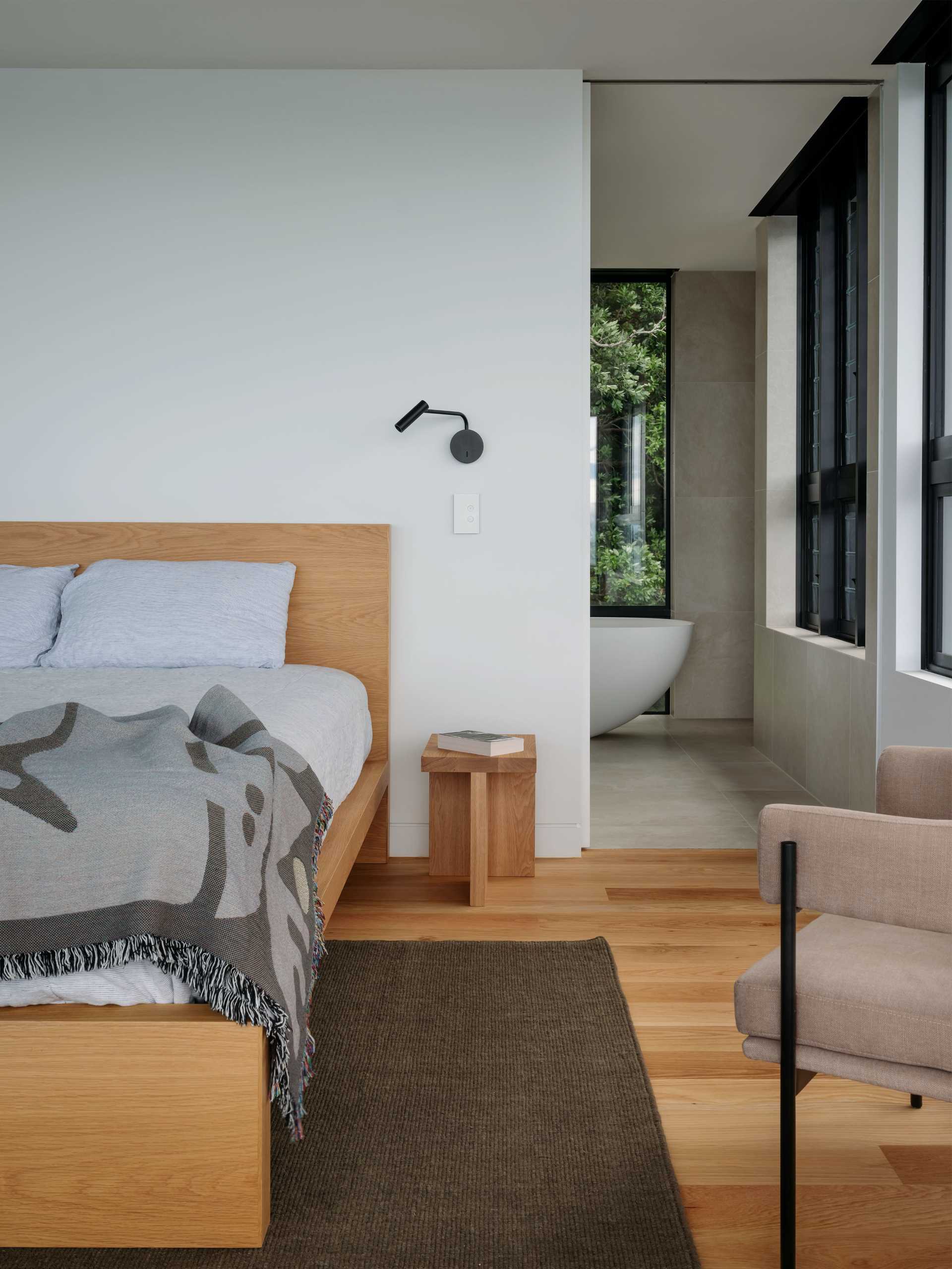 In this modern bedroom, the wood floor and wood bed frame add a sense of warmth to the space, while a tall window frames the view.