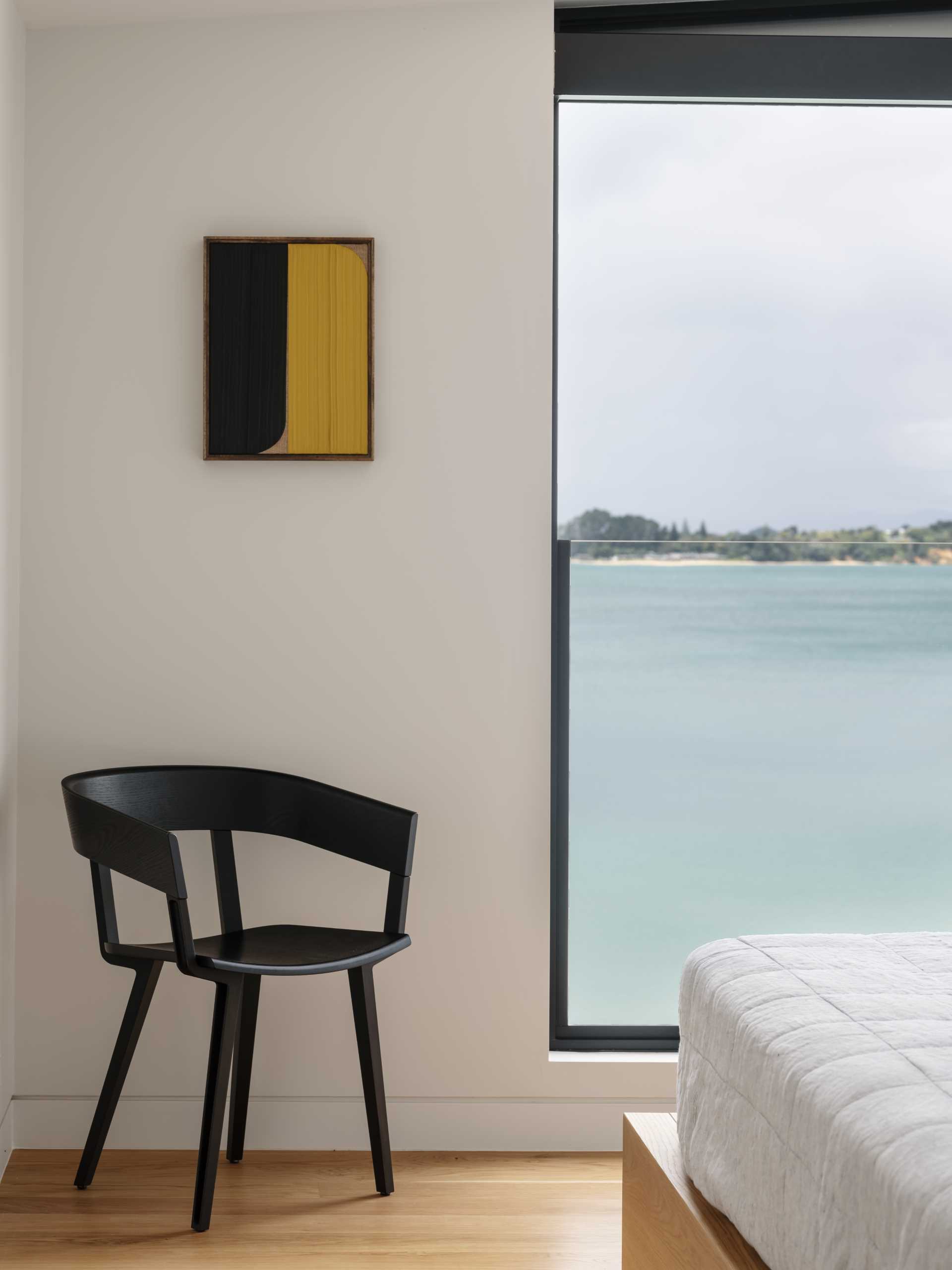 In this modern bedroom, the wood floor and wood bed frame add a sense of warmth to the space, while a tall window frames the view.