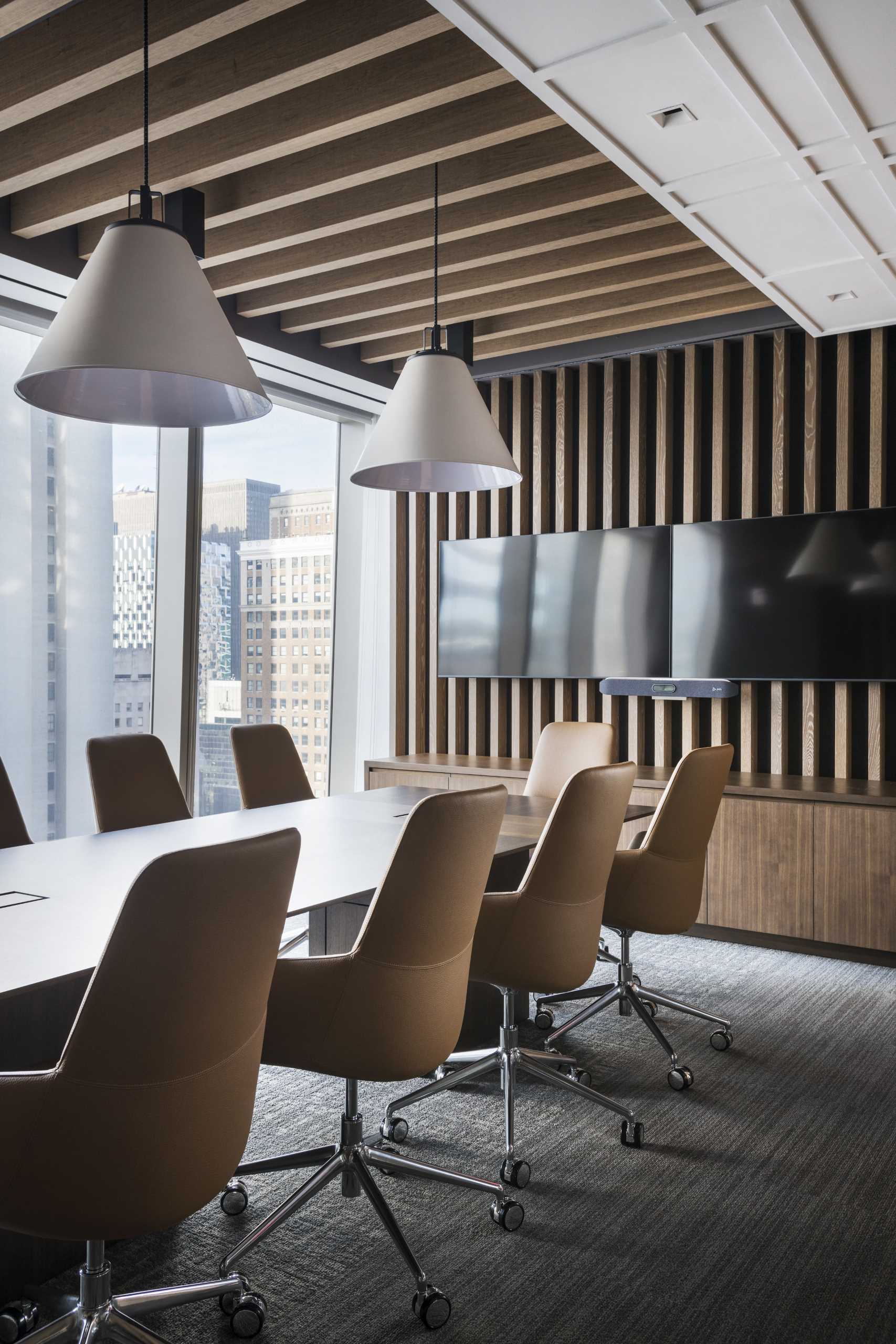 In this modern conference room, there's a wood slat wall and ceiling, which also meets with another part of the ceiling that's strapped with a white plaid pattern.