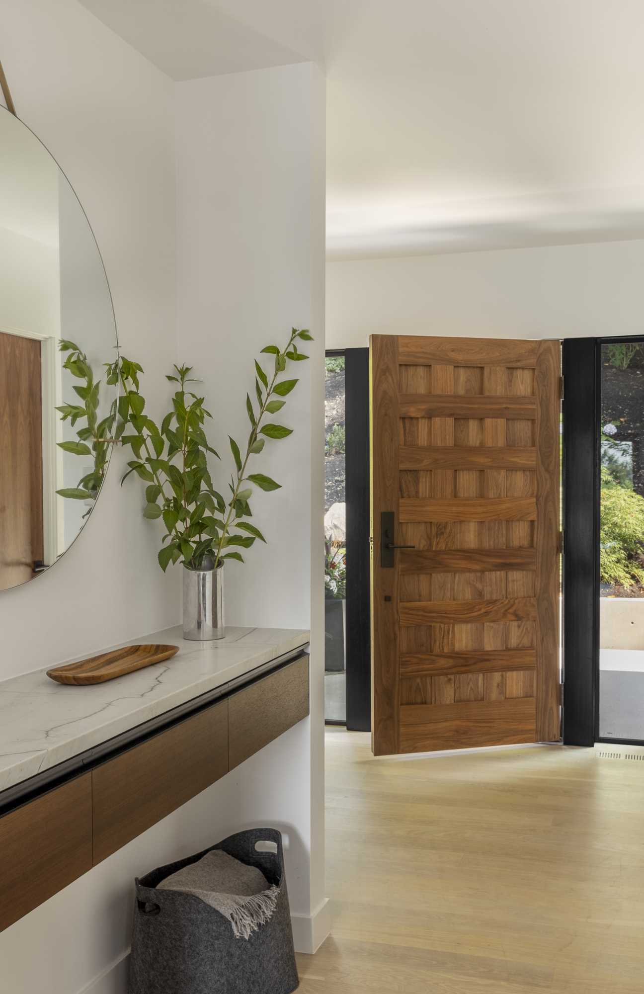 A modern entryway with a wood front door and a floating console with mirror.