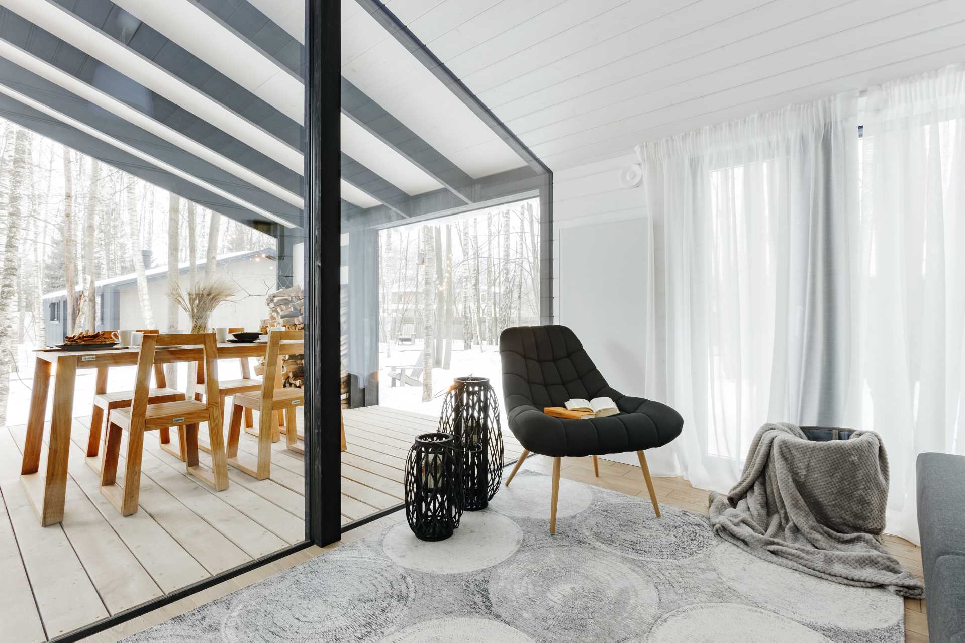 A modern den with a wall of windows that look out onto a covered deck.