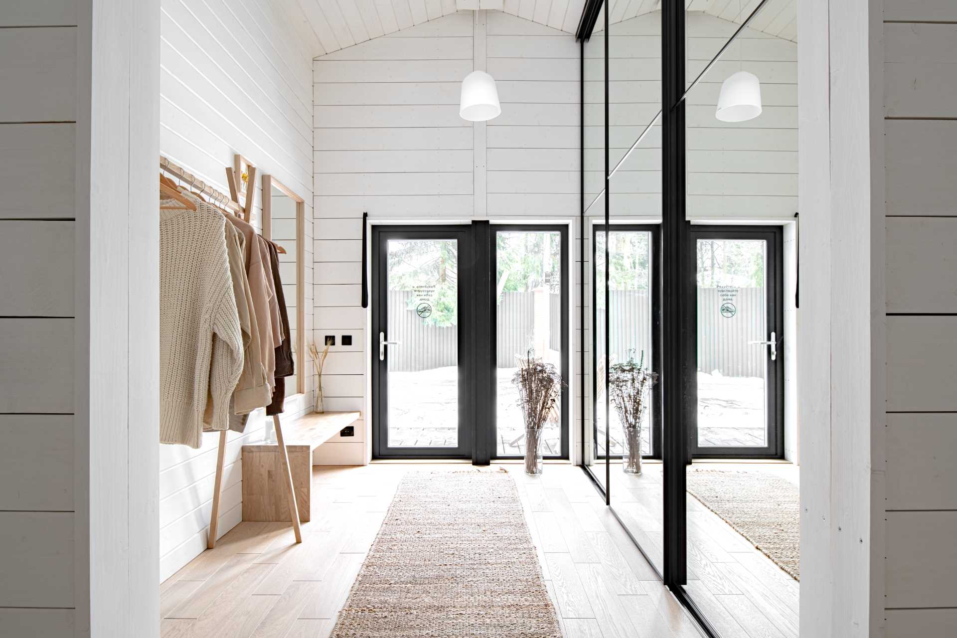 In this farmhouse-inspired entryway, there's a wood bench, a clothing rack, and a wall of mirrors that hides storage. 
