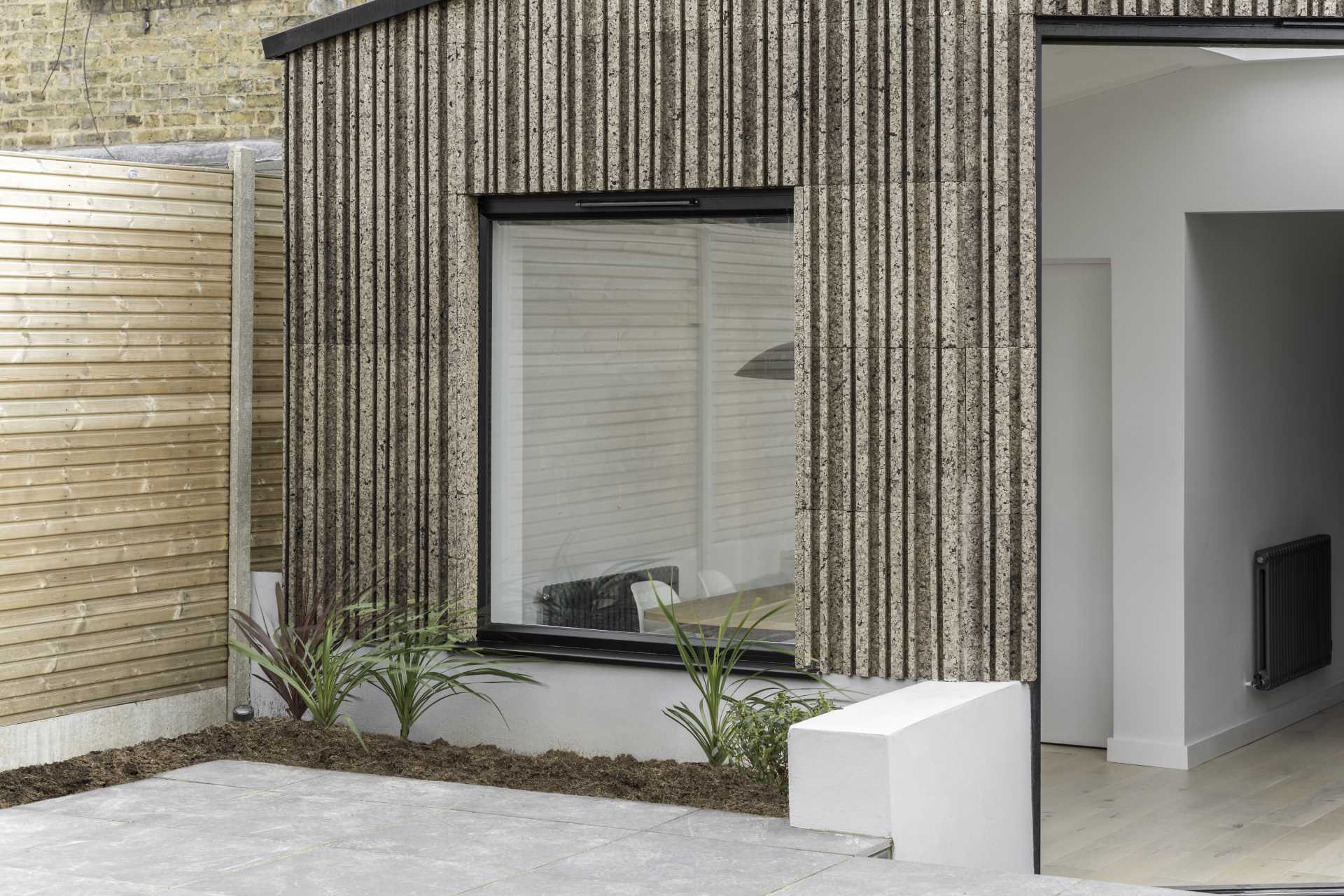 A modern home extension that's clad in patterned cork, and includes black window frames.