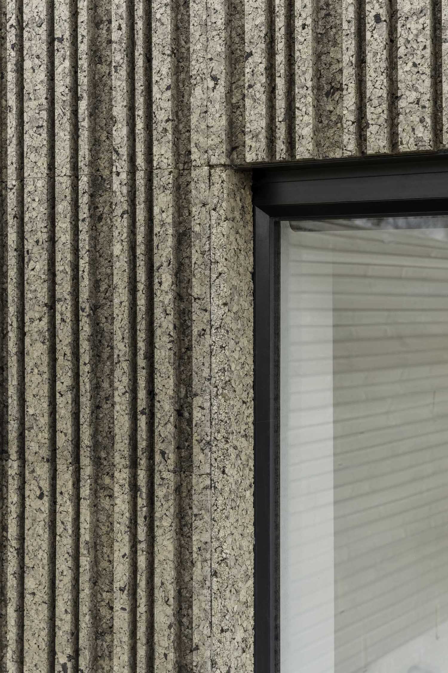 A modern home extension that's clad in patterned cork, and includes black window frames.