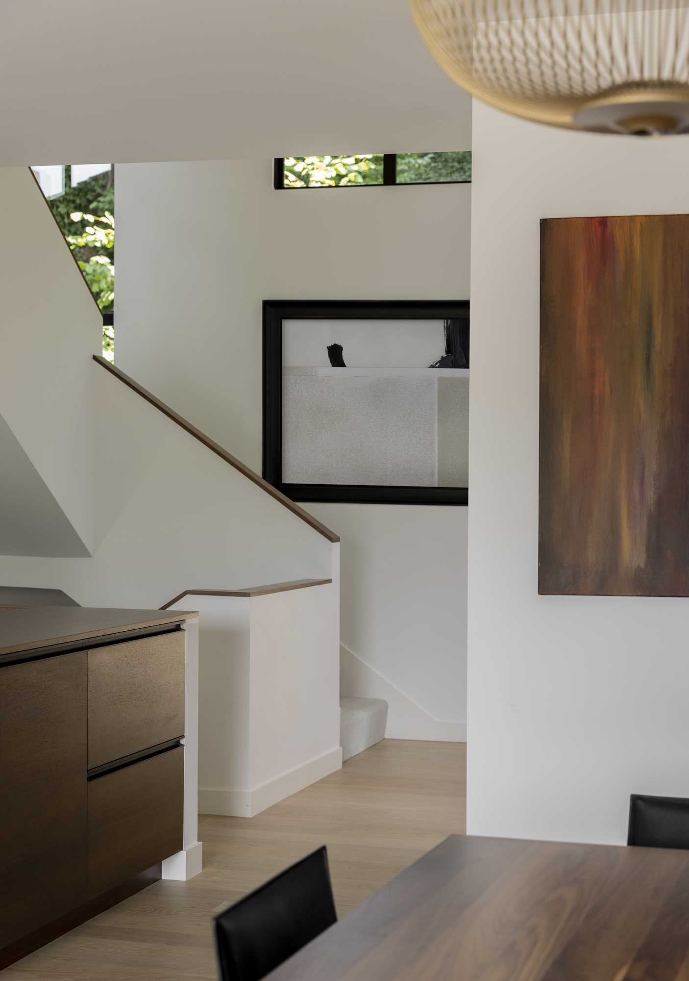 The new stairs in this remodeled home were designed to be bright with light-colored walls, light flooring, and minimal wood handrails.