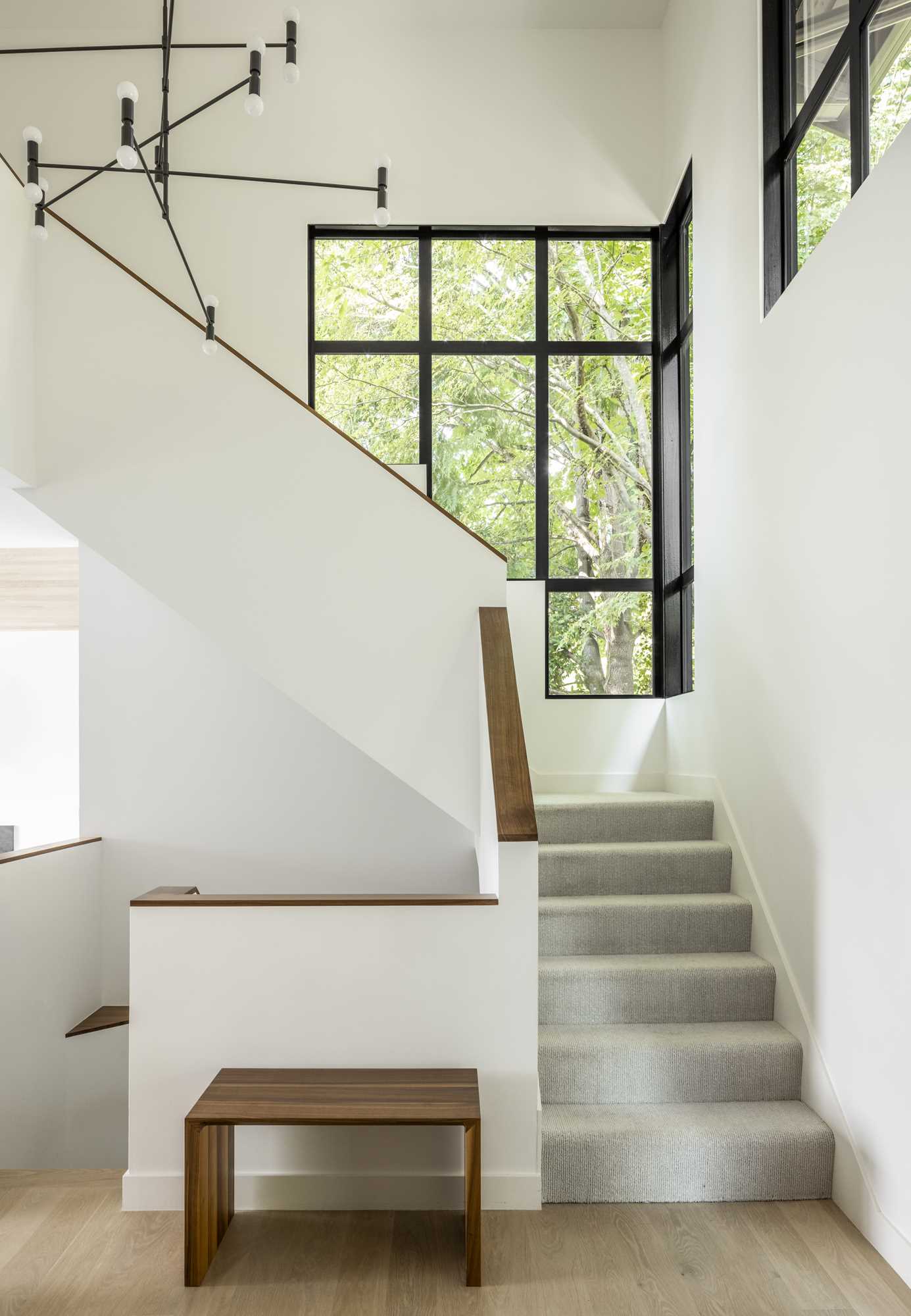 The new stairs in this remodeled home were designed to be bright with light-colored walls, light flooring, and minimal wood handrails.