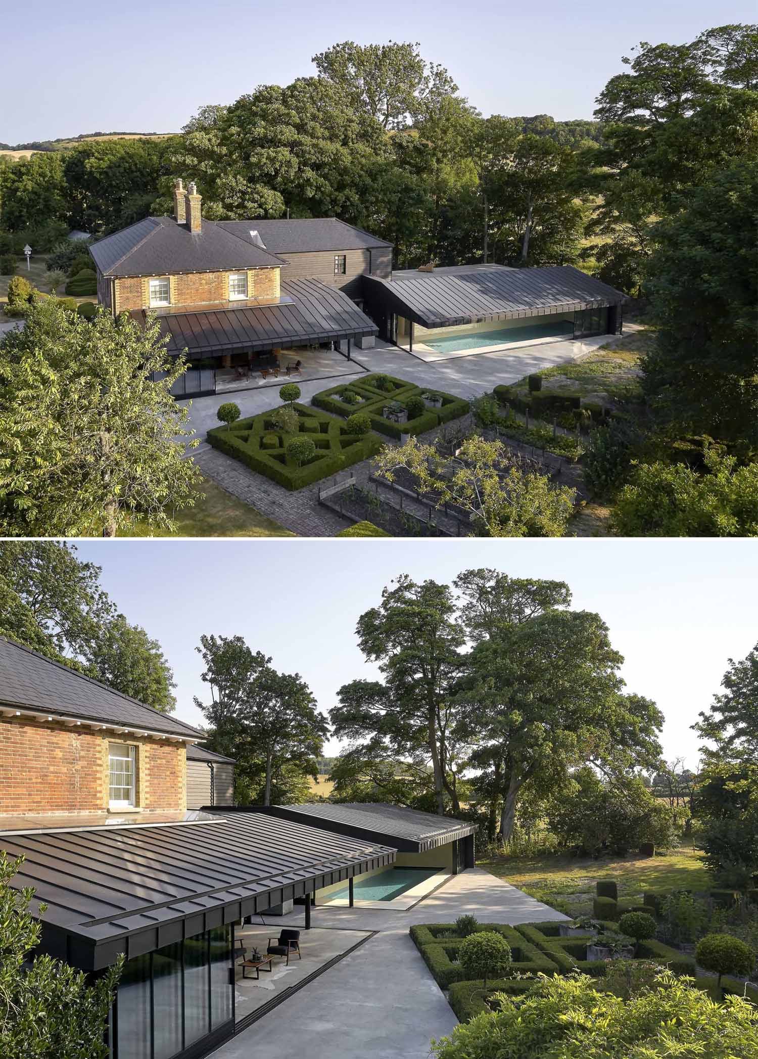 A modern black house extension has sliding glass walls that open the living spaces to the landscaped garden.