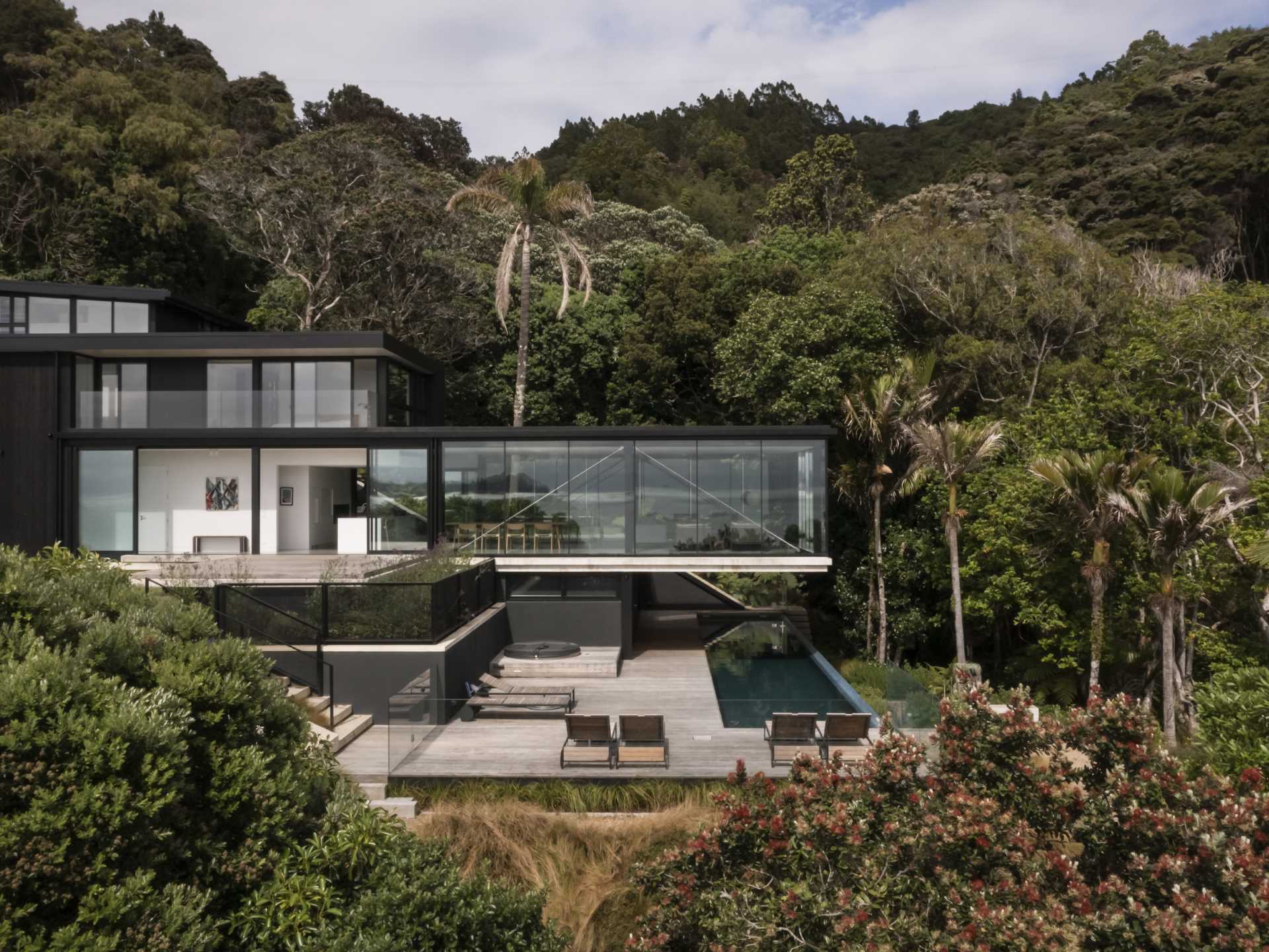 A modern home with a living room that overhangs the swimming pool below.