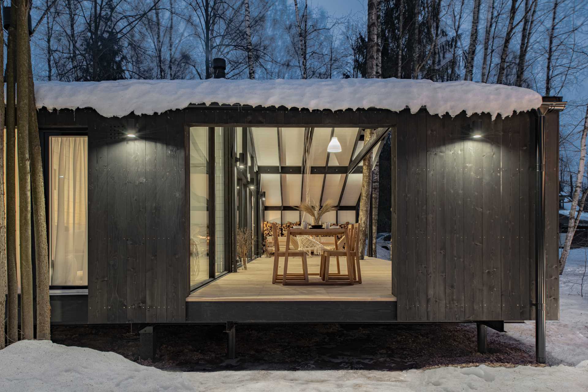 A modular home with a covered outdoor space for entertaining and storing wood.