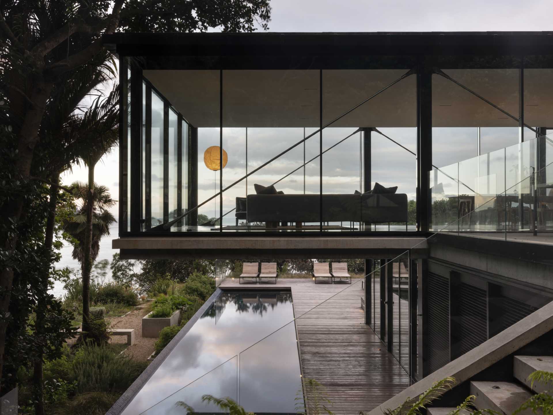 A modern home with a living room that overhangs above the swimming pool below.