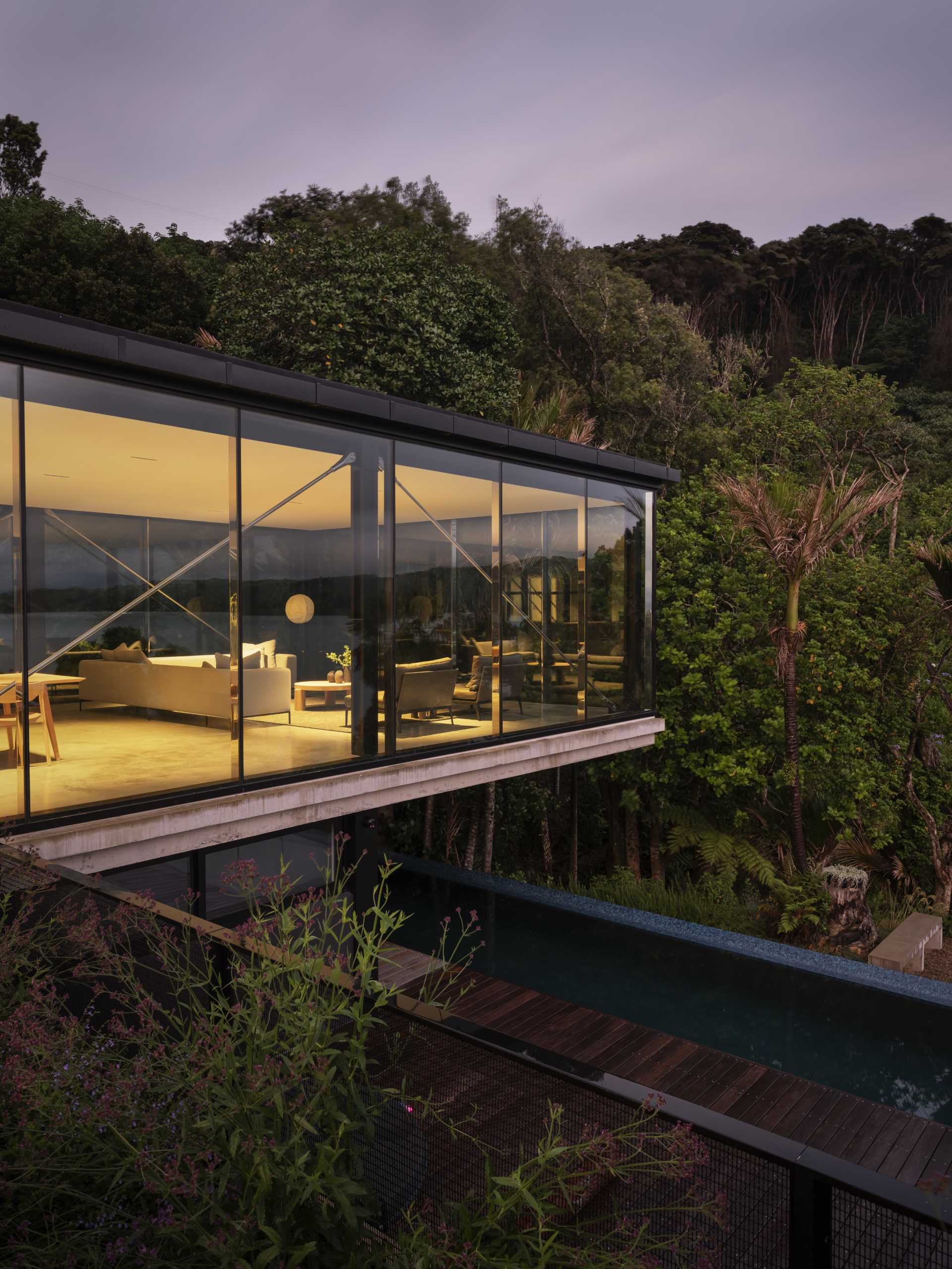 A modern home with a living room that overhangs above the swimming pool below.