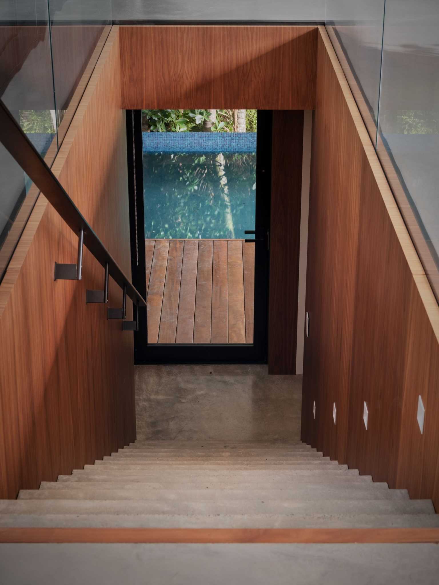 A modern home with stairs leading down to the pool.