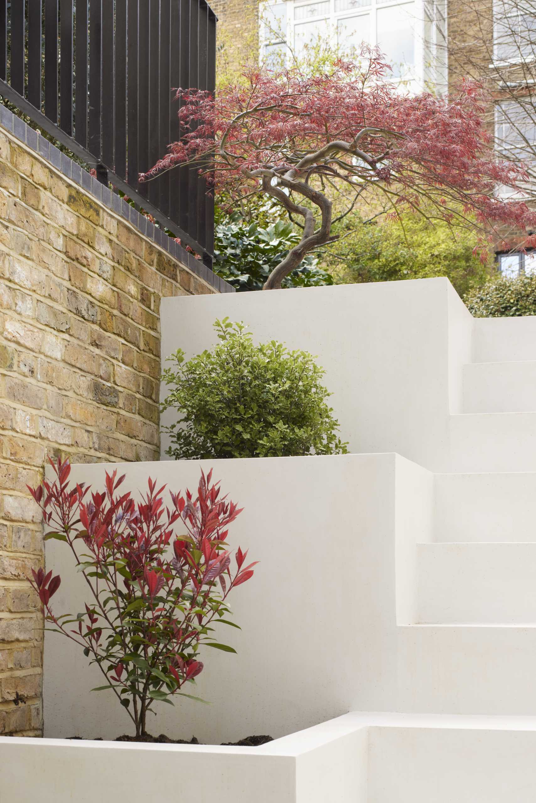 Outdoor stairs with built-in planters filled with small trees and shrubs.