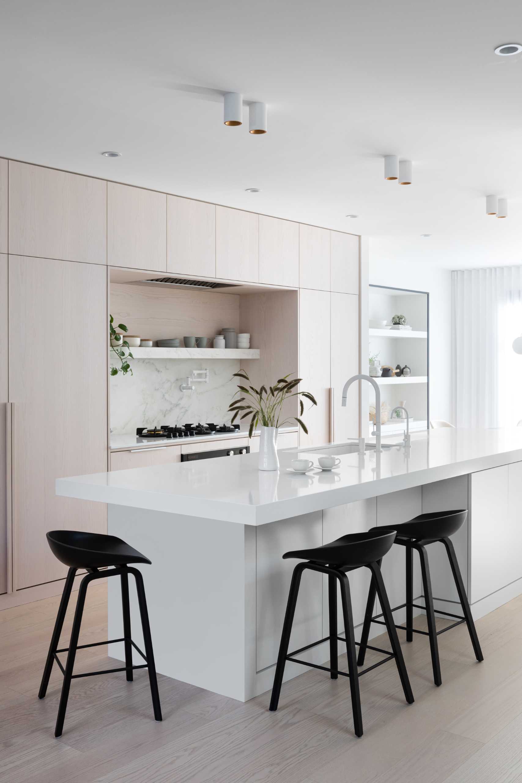 In this modern kitchen, there's white stained oak, cool white marble, and black accents.