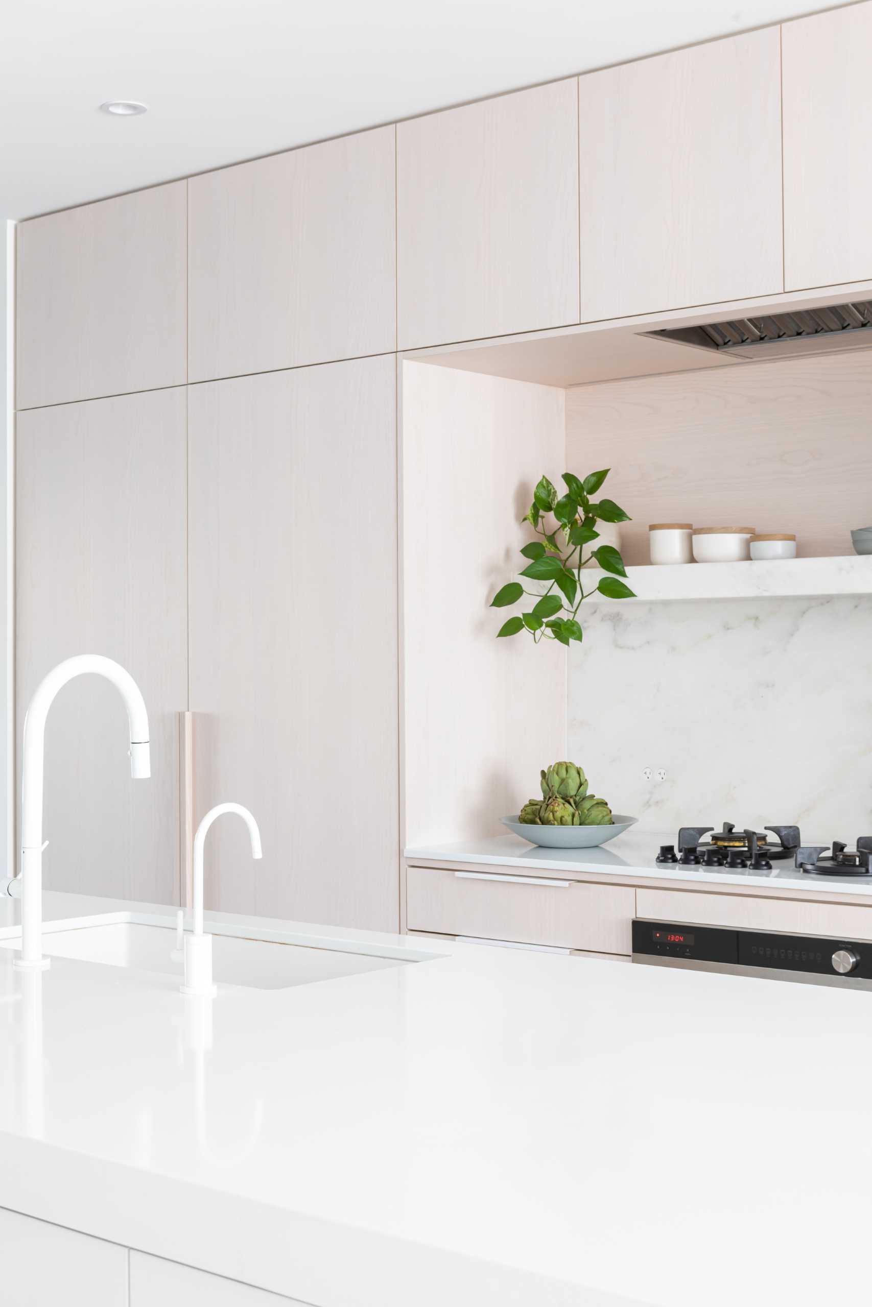 In this modern kitchen, there's white stained oak, cool white marble, and black accents.