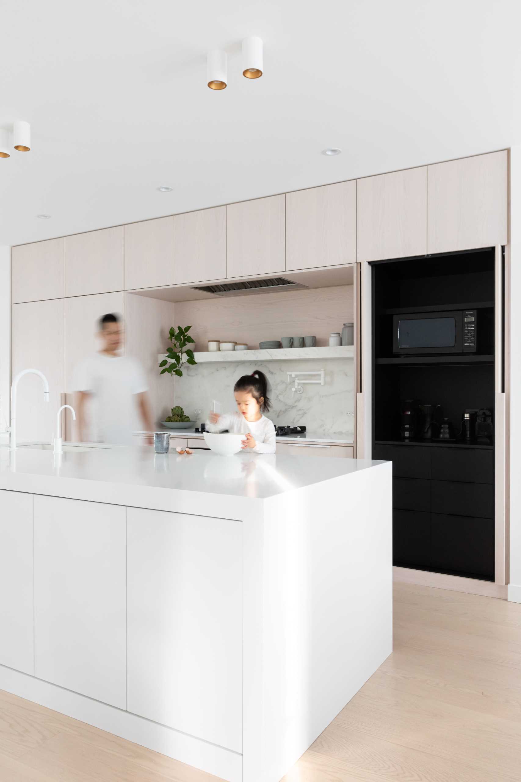 In this modern kitchen, there's white stained oak, cool white marble, and black accents.