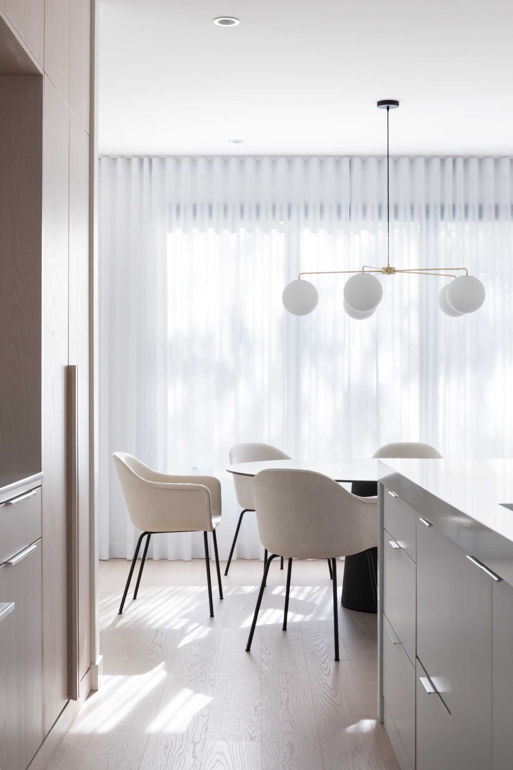 Sheer curtains bathe the dining room and kitchen with diffused sunlight from the front of the home.