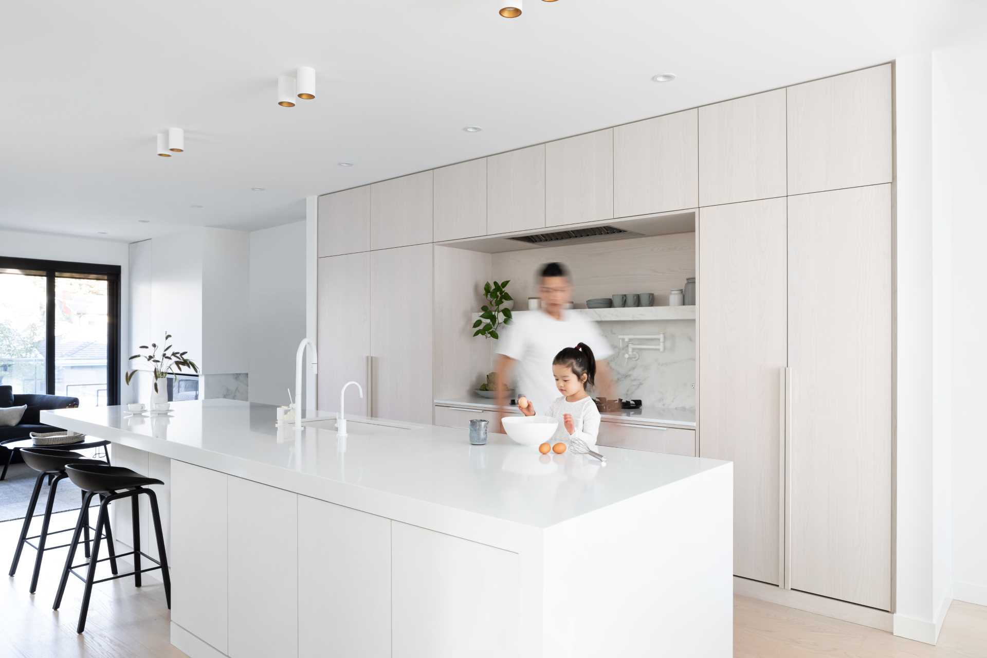 In this modern kitchen, there's white stained oak, cool white marble, and black accents.