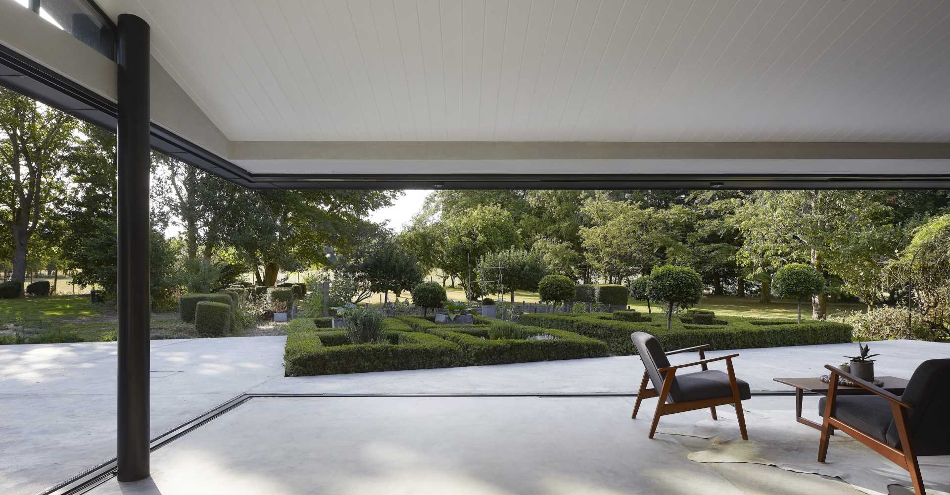 A modern house extension has sliding glass walls that open the living spaces to the landscaped garden.