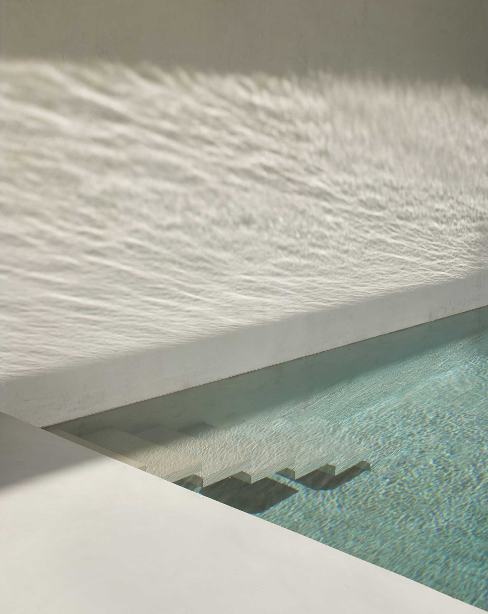 A modern pool design with cantilevered stairs leading into the water.