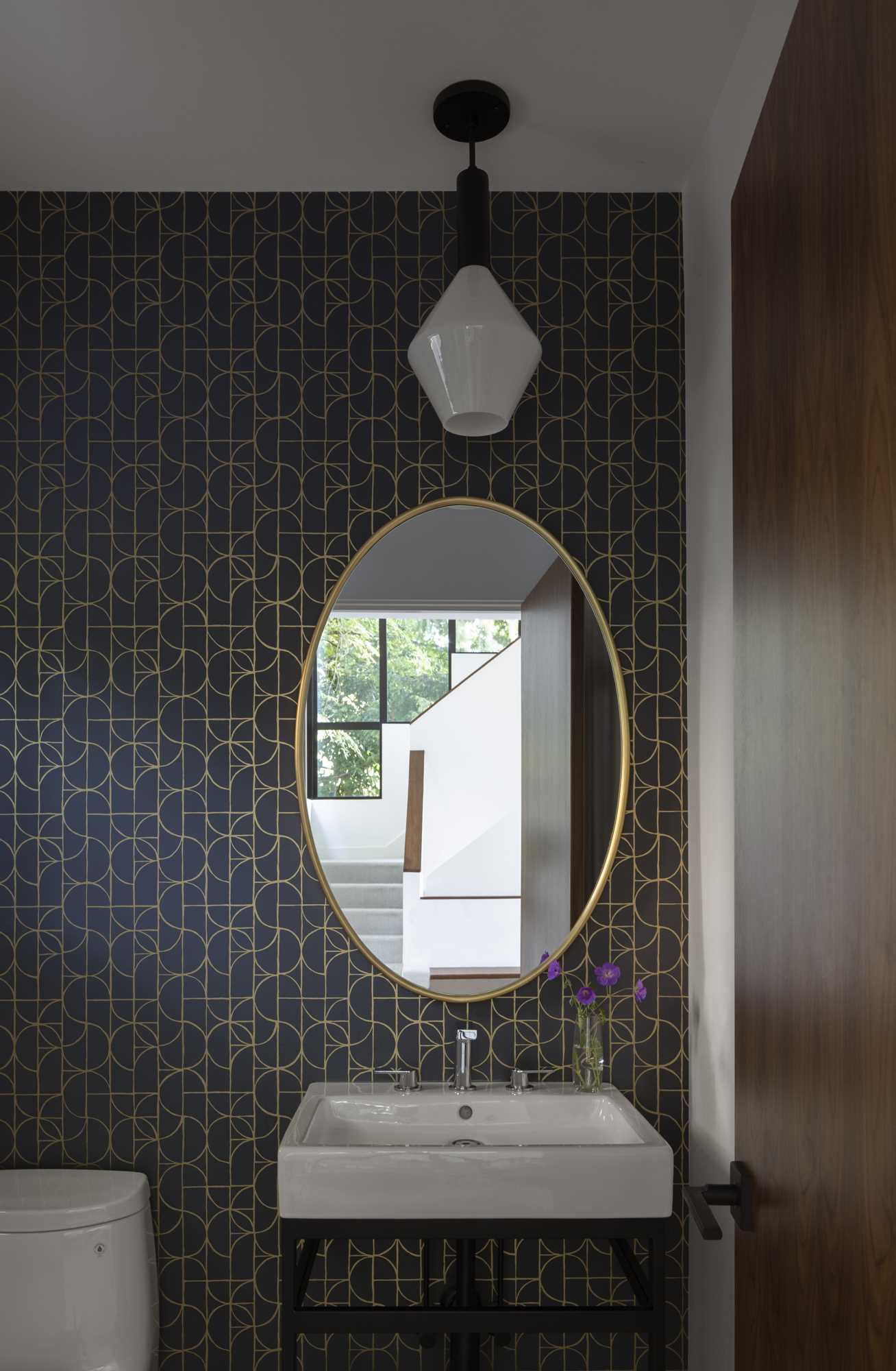 A modern powder room with a black and gold wallpaper.