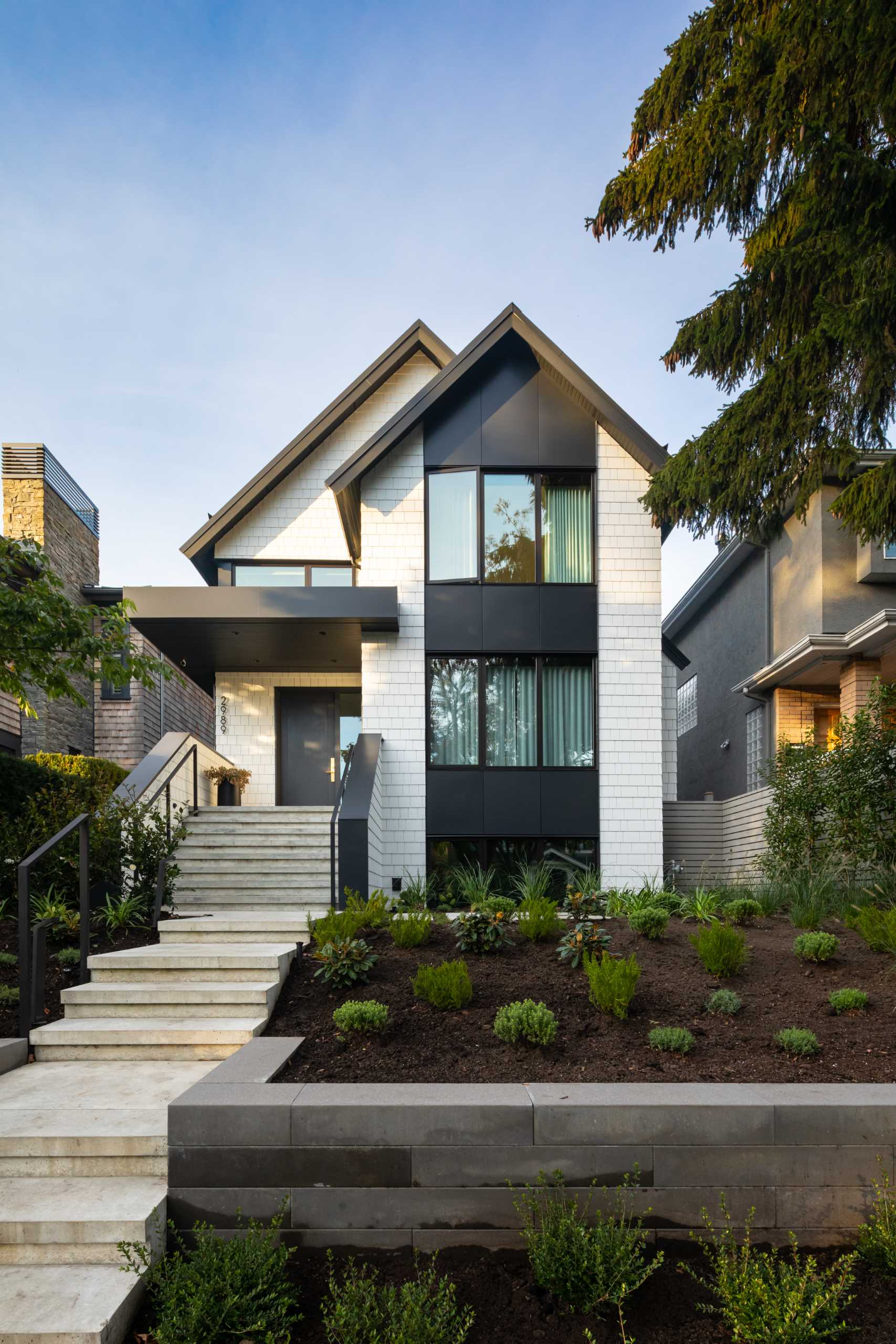 A contemporary home with white shingles and black accents.
