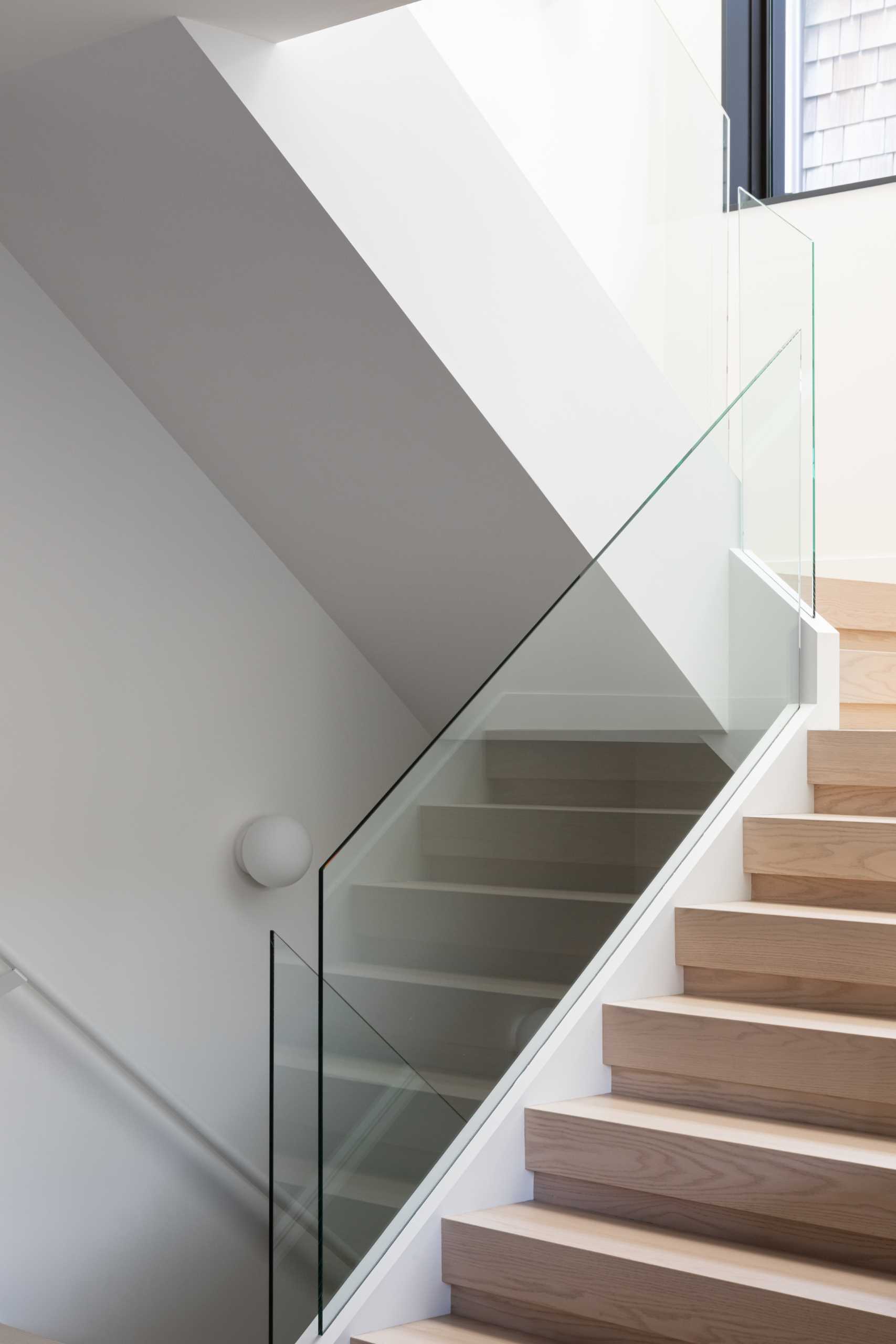 Wood stairs with a glass railing connect the various levels of this modern home.