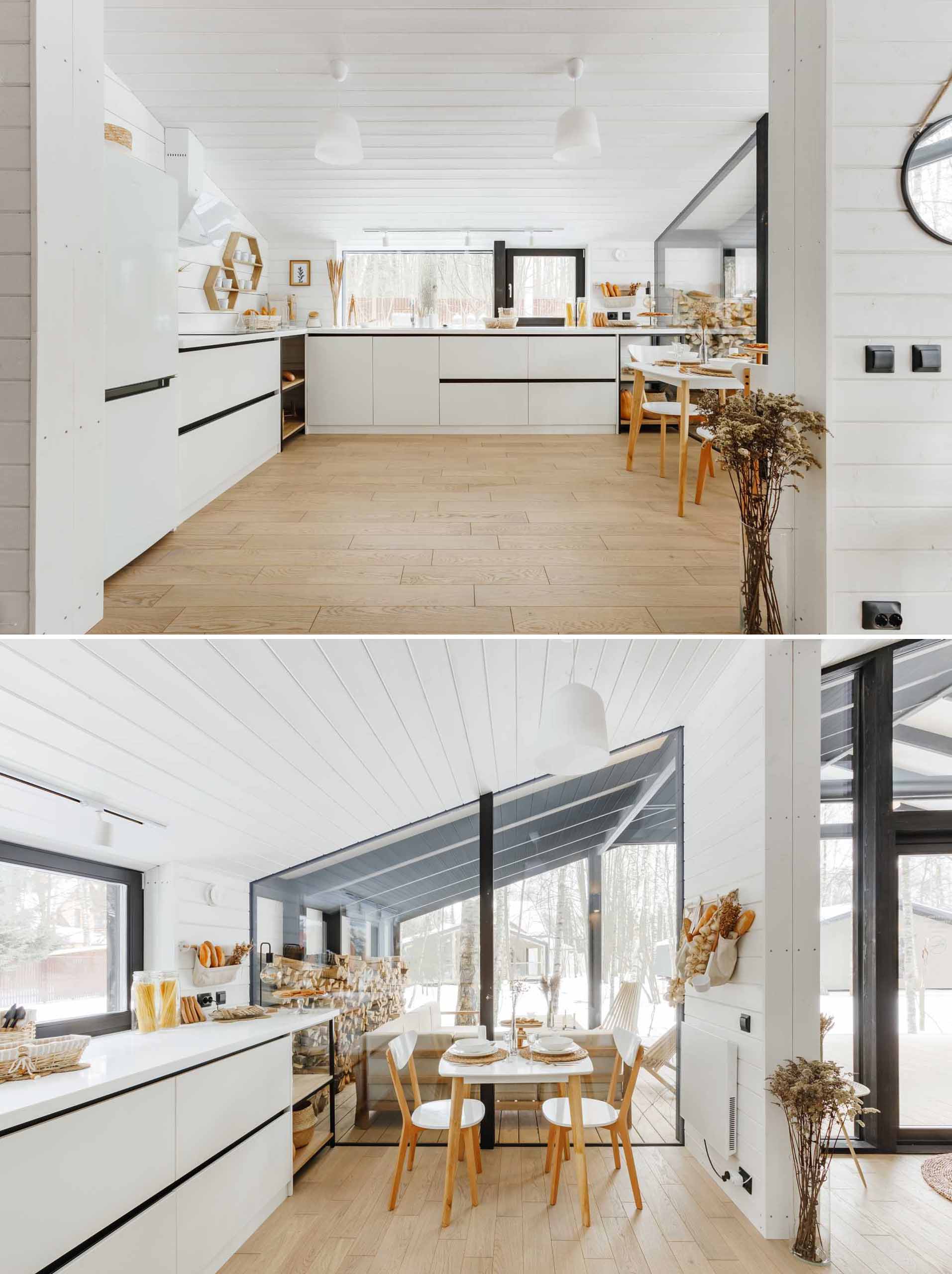 یک آشپزخانه مدرن با کابینت های سفید، کف چوبی و یک گوشه کوچک صبحانه.