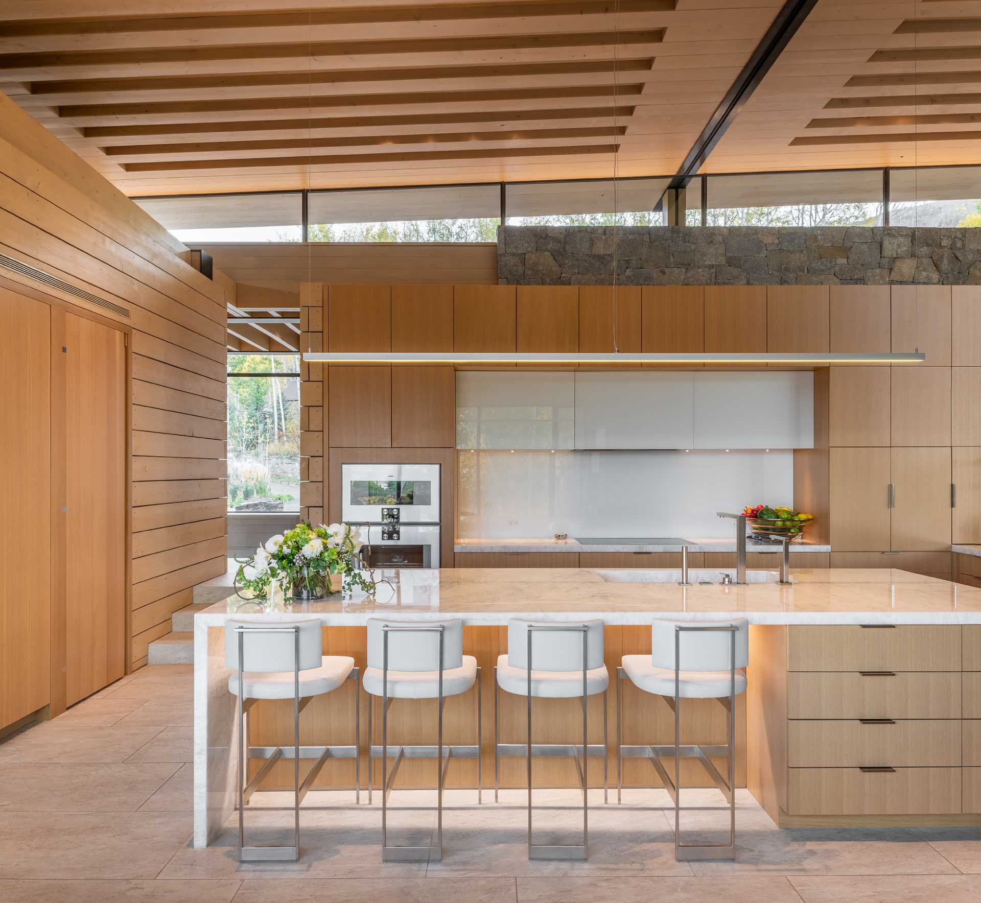 Clerestory windows in the wood kitchen allow for natural light to fill the interior, while a large island includes storage and a place for seating.