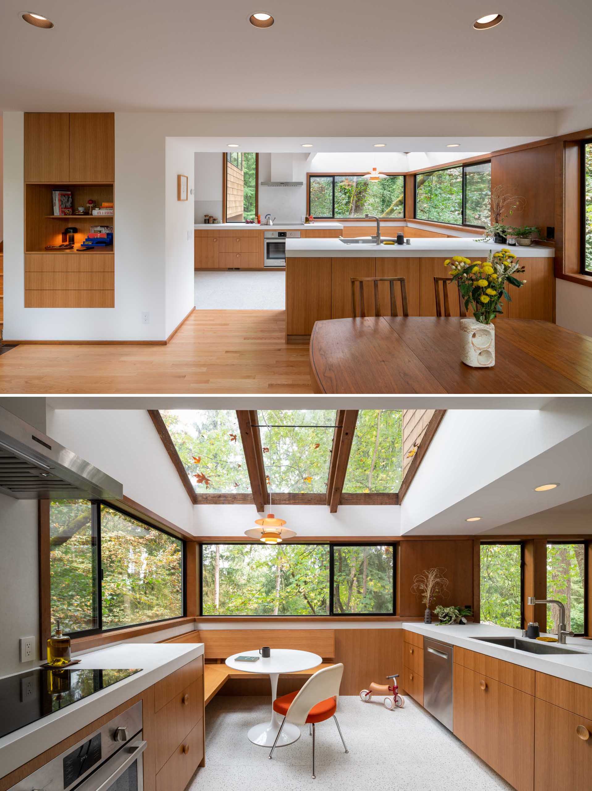 A remodeled kitchen with a built-in corner breakfast nook underneath the skylights and next to windows with forest views.