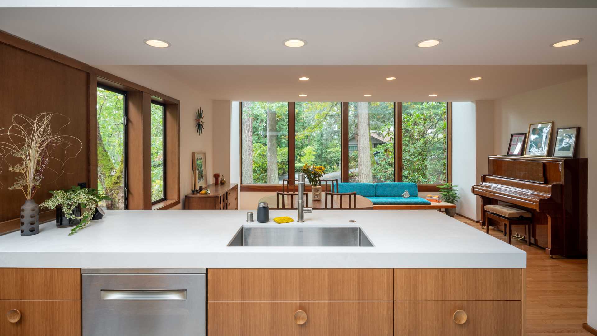 A new and open kitchen looks out onto the dining area and forest beyond.