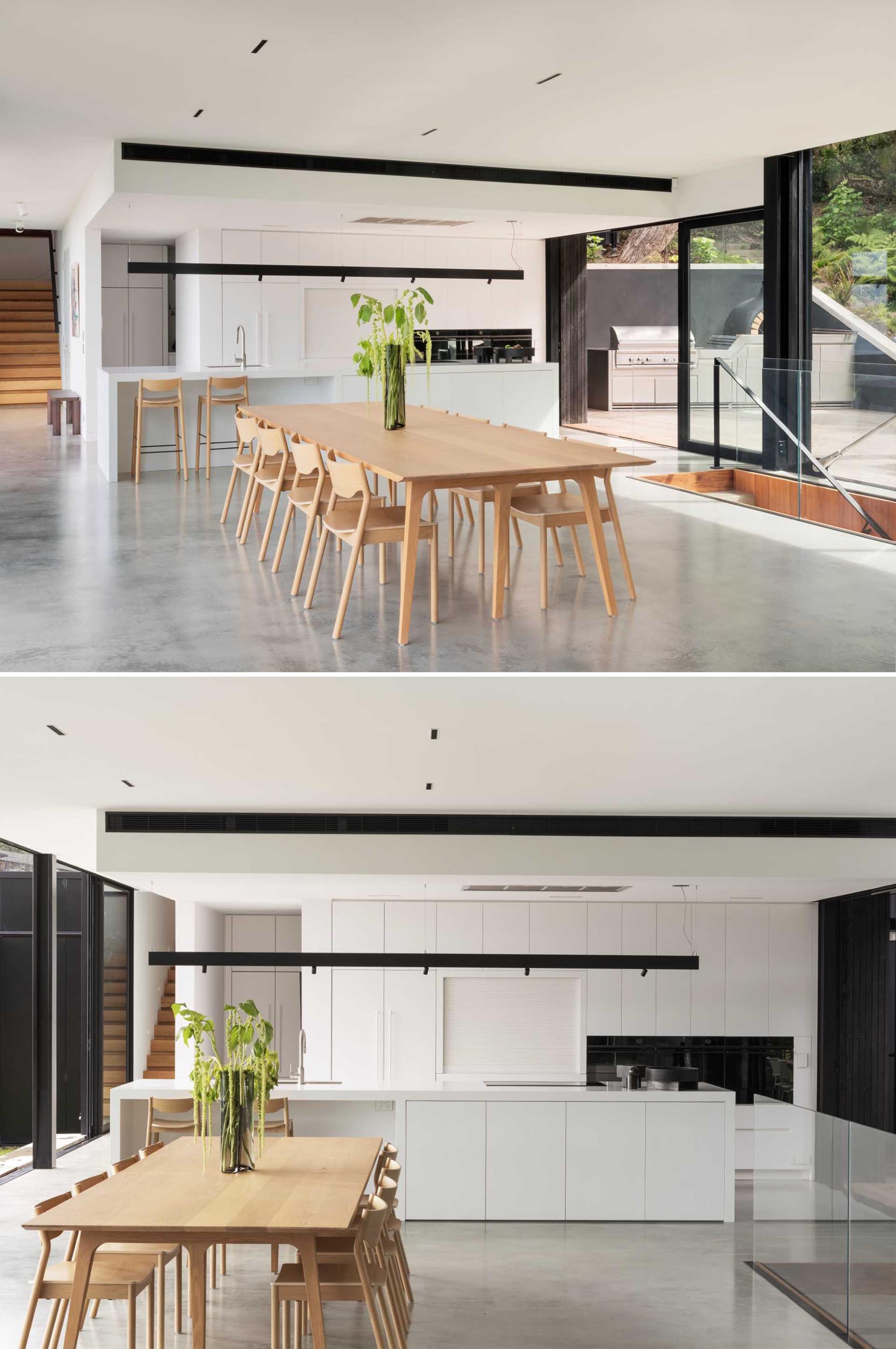 A minimalist white kitchen with a large island an concrete floor.