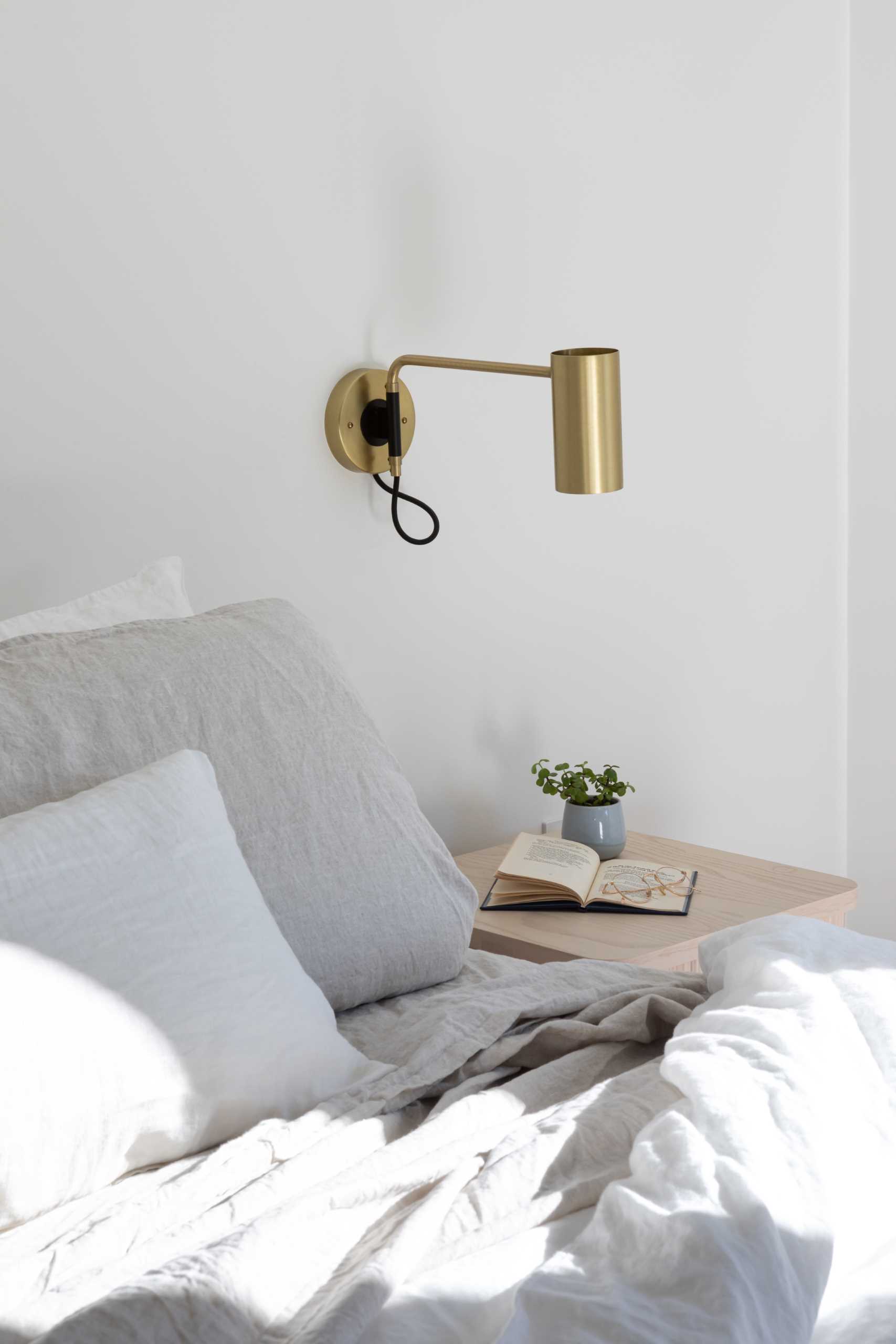 In this modern primary bedroom, a vaulted ceiling and white walls create a large yet calming space.